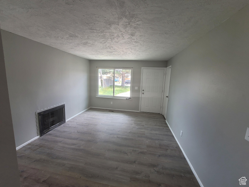 Unfurnished living room with dark wood-type flooring and a textured ceiling