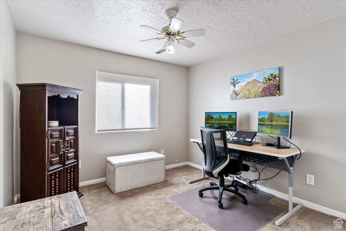 Office space featuring a textured ceiling, light colored carpet, and ceiling fan