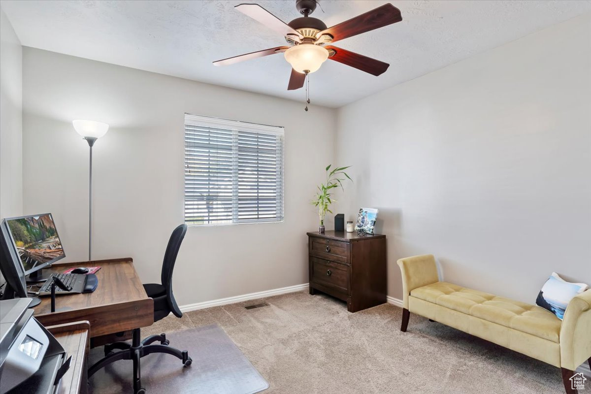 Home office featuring light colored carpet and ceiling fan