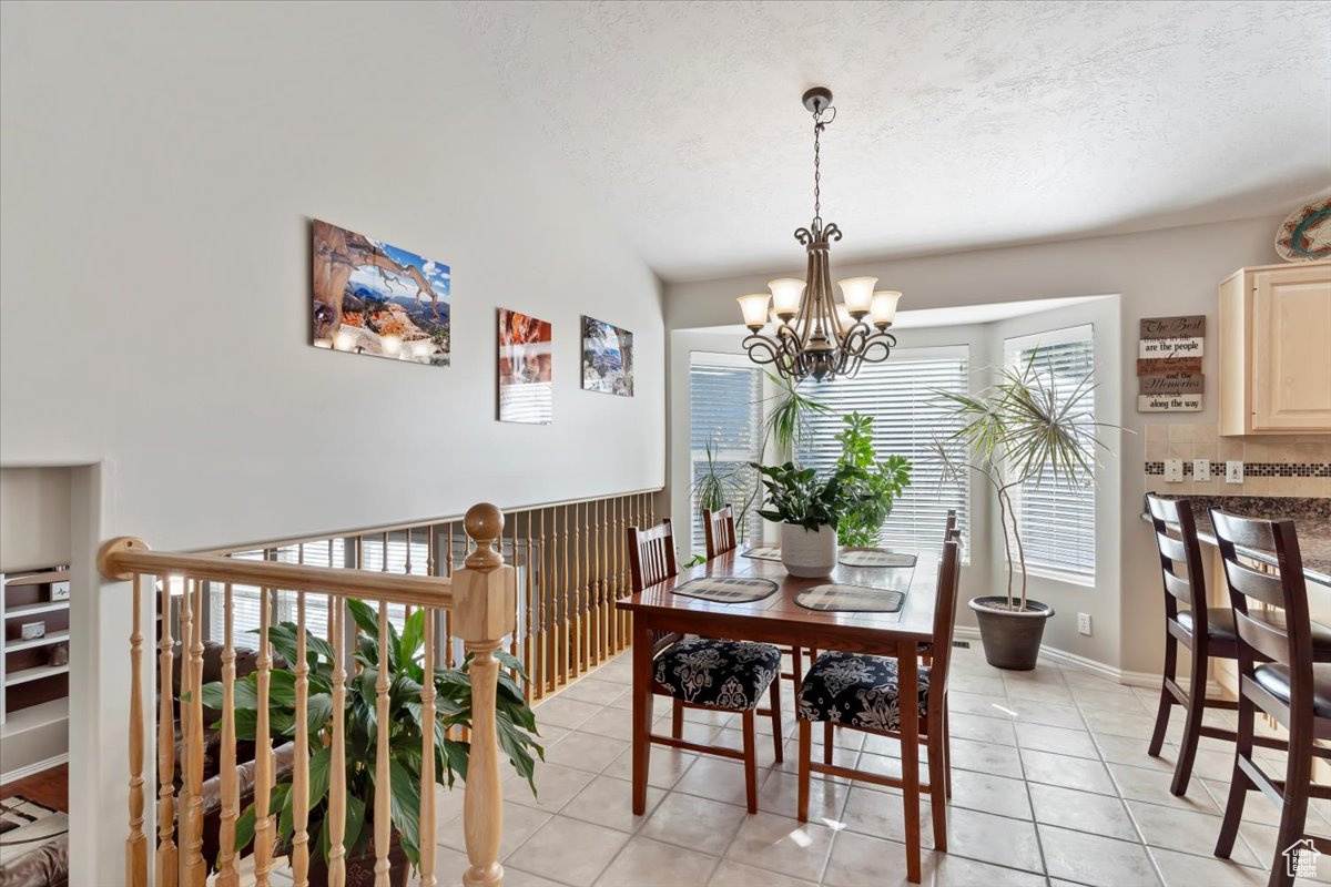 Dining room featuring a textured ceiling, a notable chandelier, and light tile patterned floors