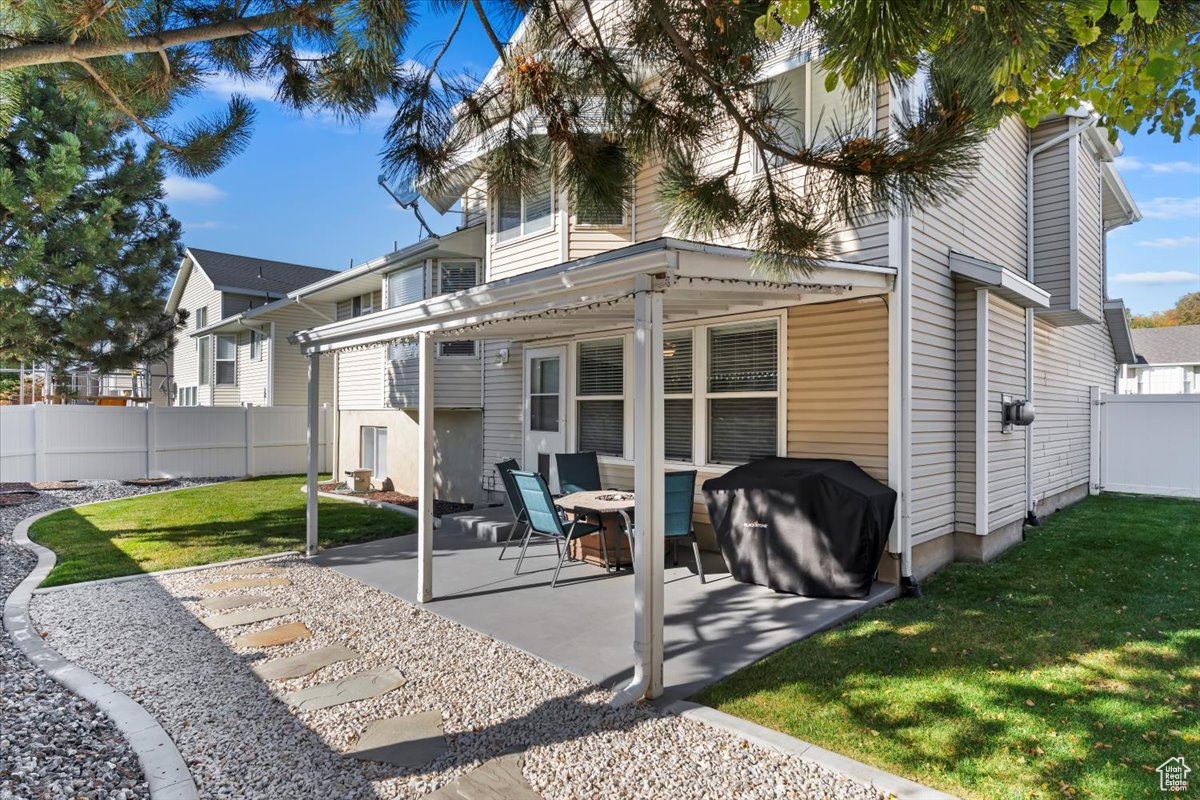 Rear view of property with a patio area, a pergola, and a lawn