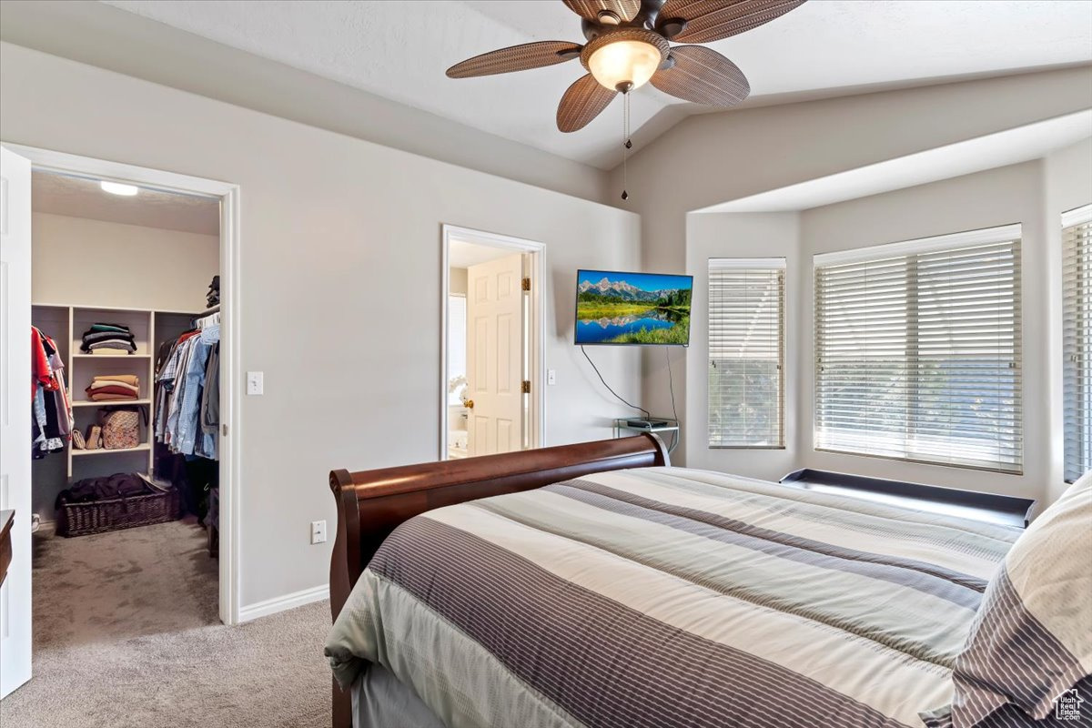 Bedroom featuring vaulted ceiling, light carpet, ceiling fan, a closet, and a spacious closet