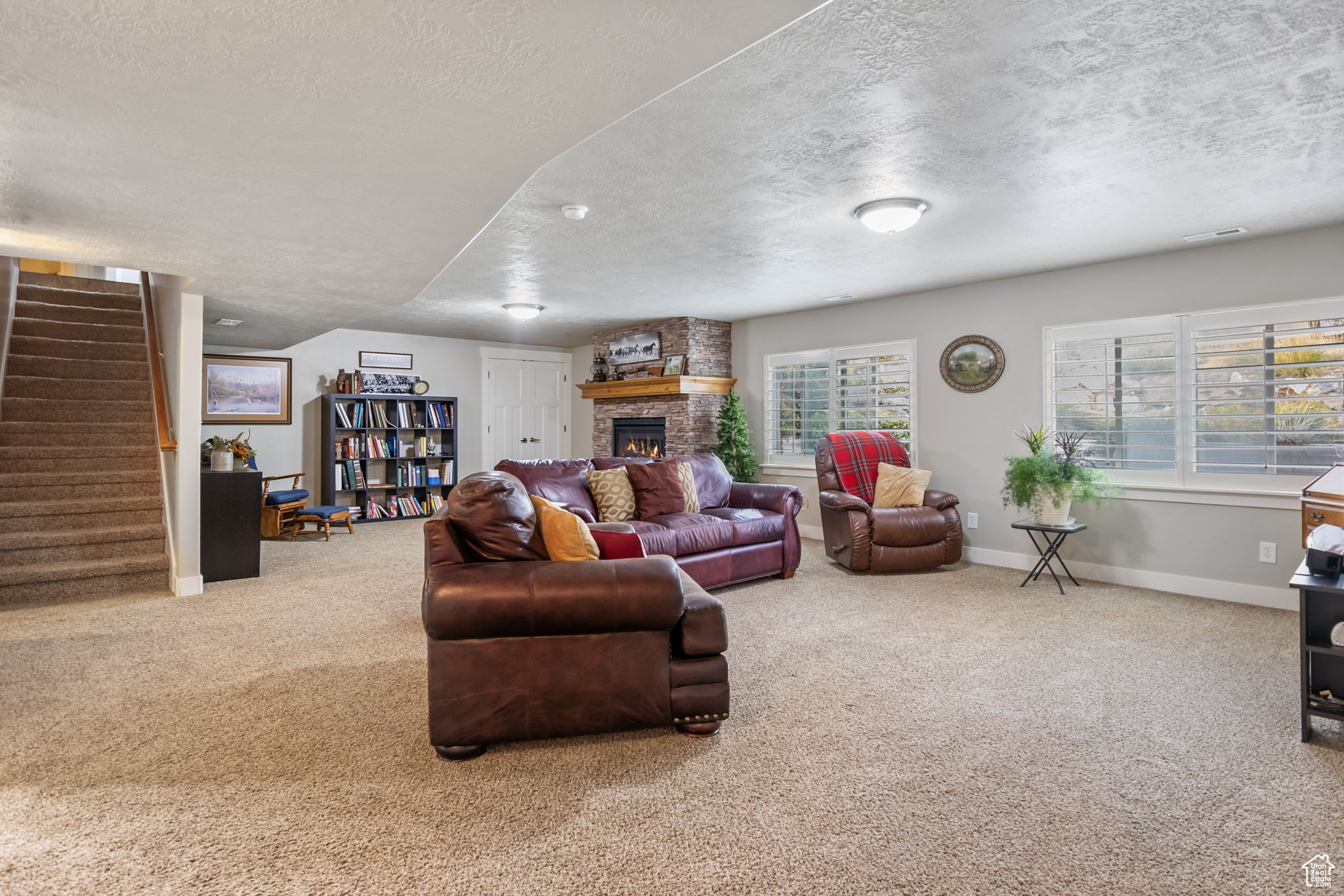 Carpeted living room with a fireplace, a healthy amount of sunlight, and a textured ceiling