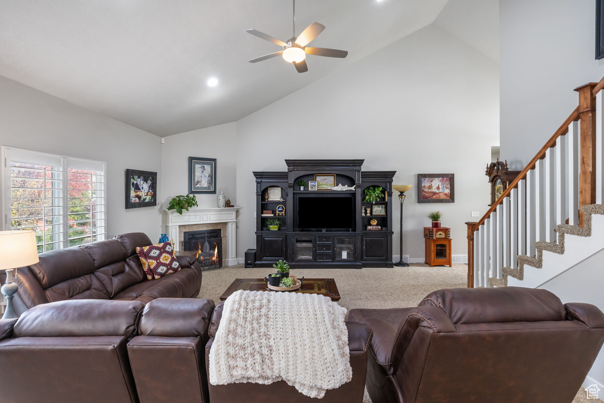 Living room with carpet, ceiling fan, and high vaulted ceiling