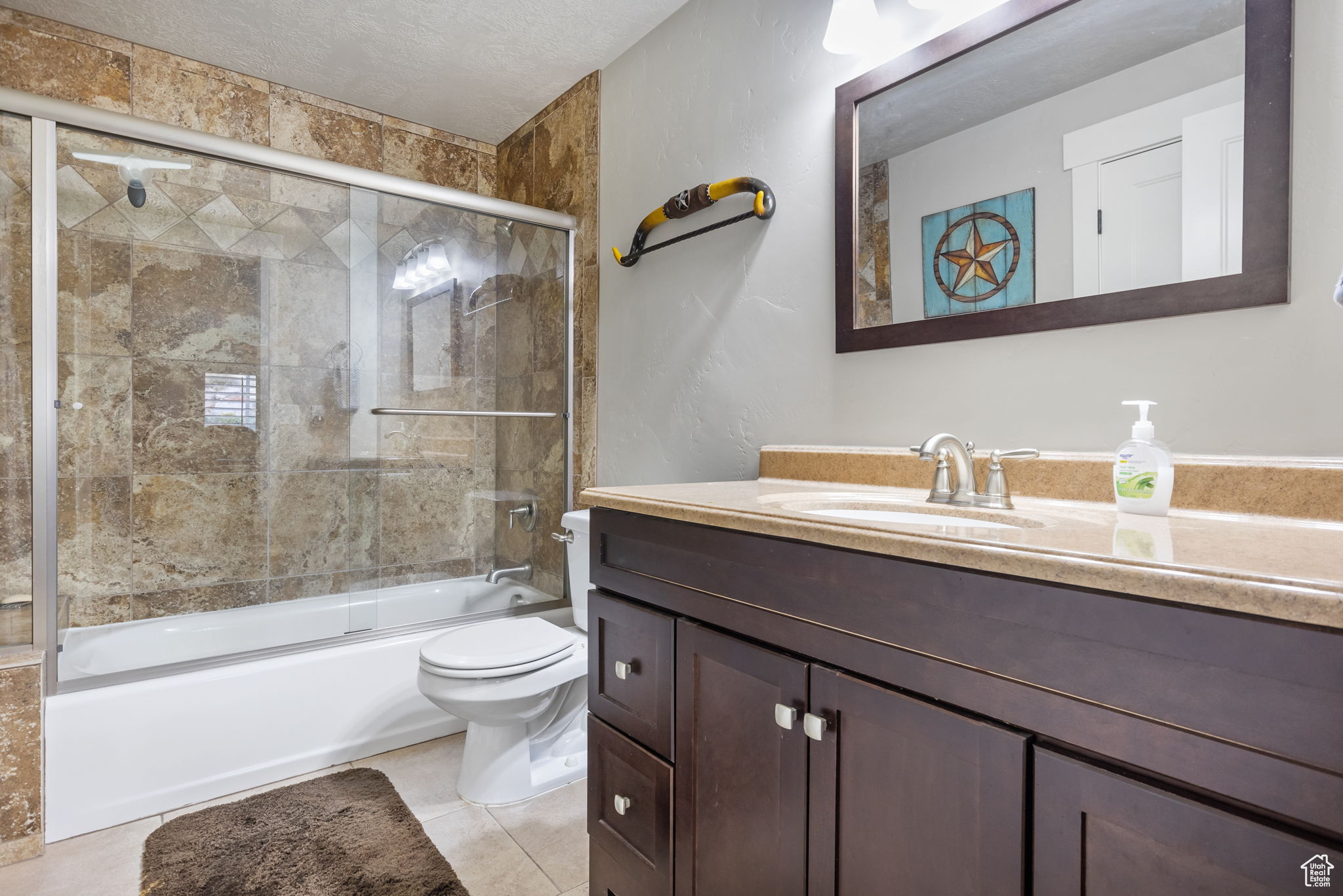 Full bathroom featuring tile patterned floors, vanity, a textured ceiling, enclosed tub / shower combo, and toilet