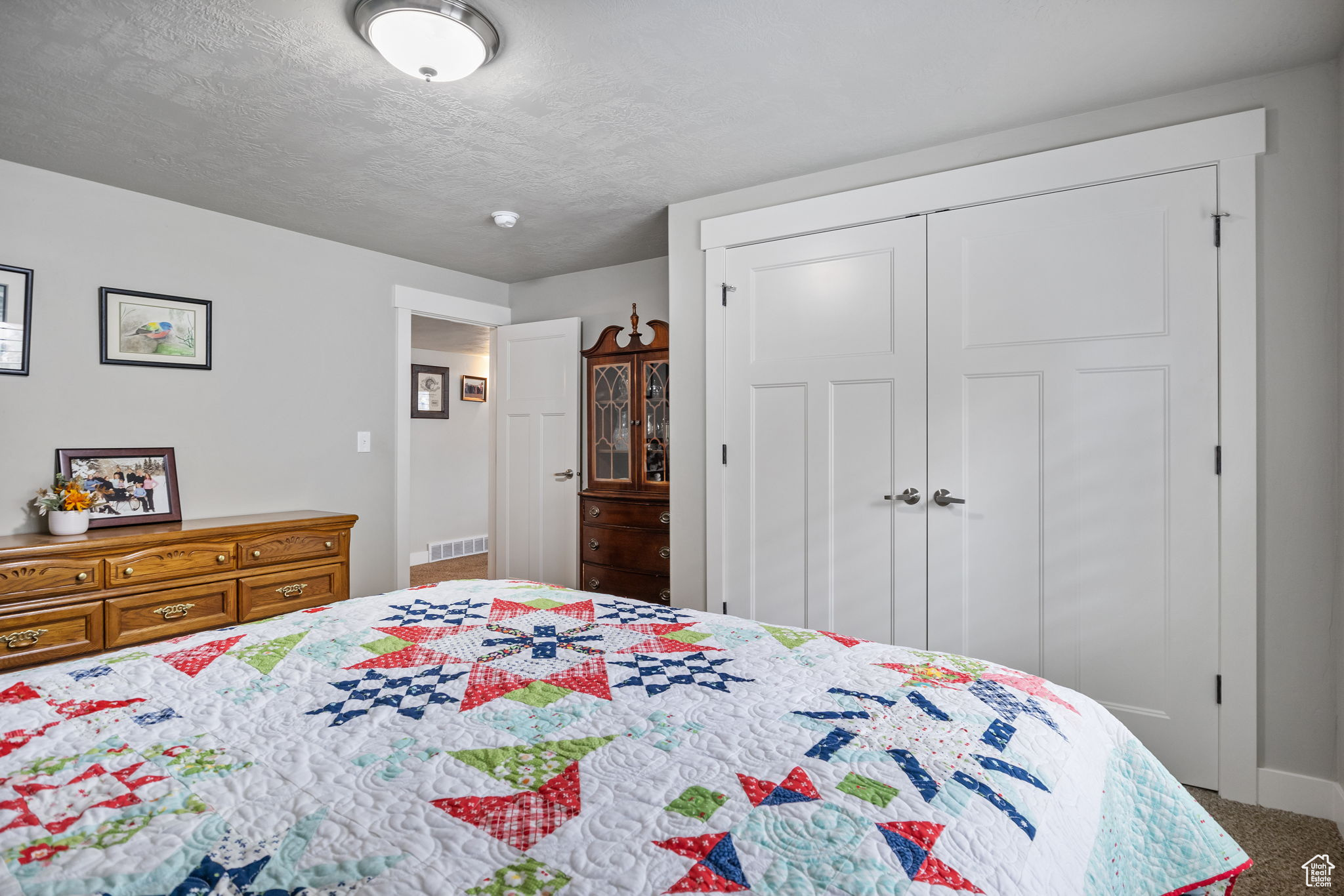 Bedroom with a closet, carpet floors, and a textured ceiling