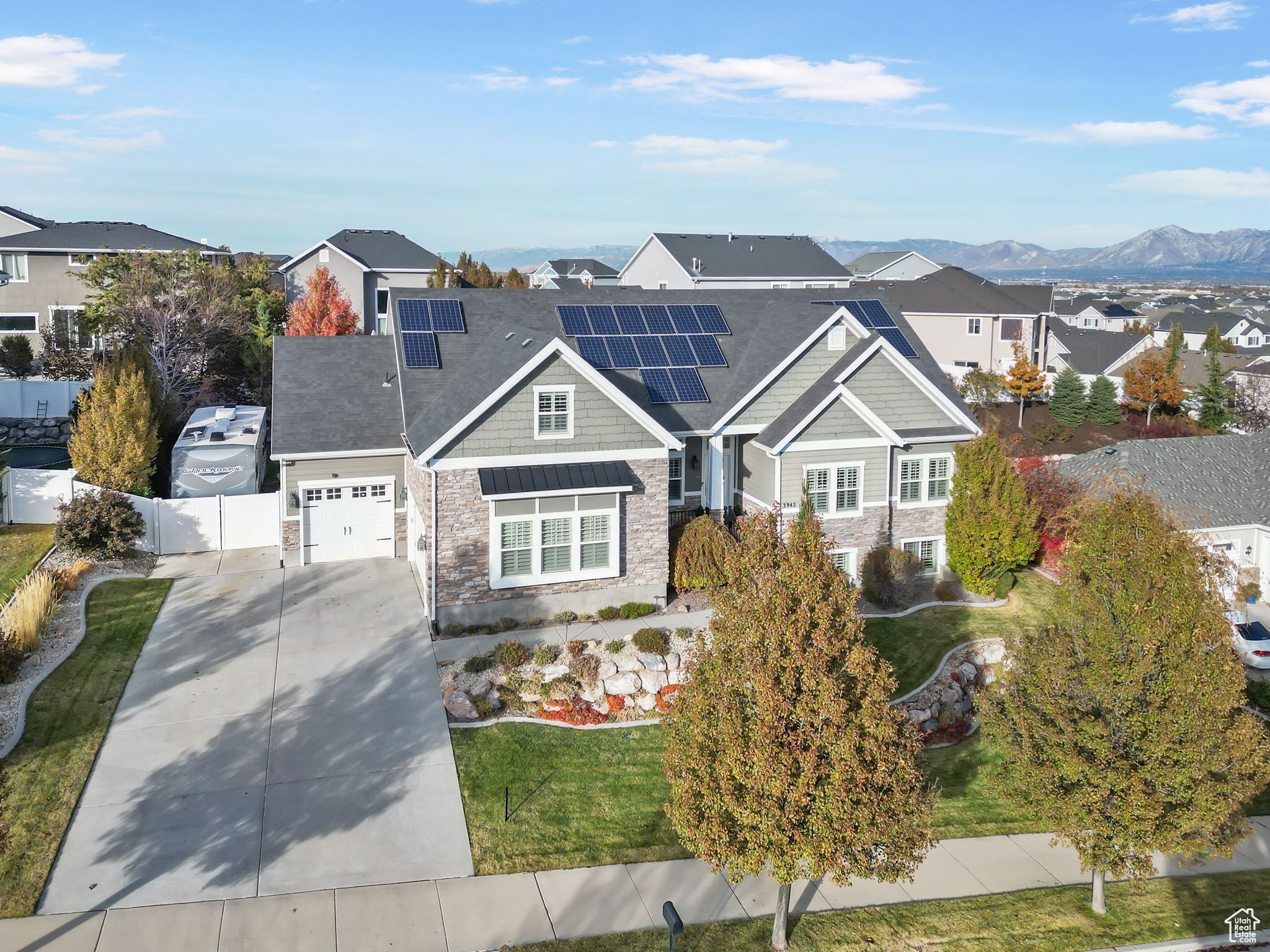 View of front of property with a front lawn, a mountain view, and solar panels