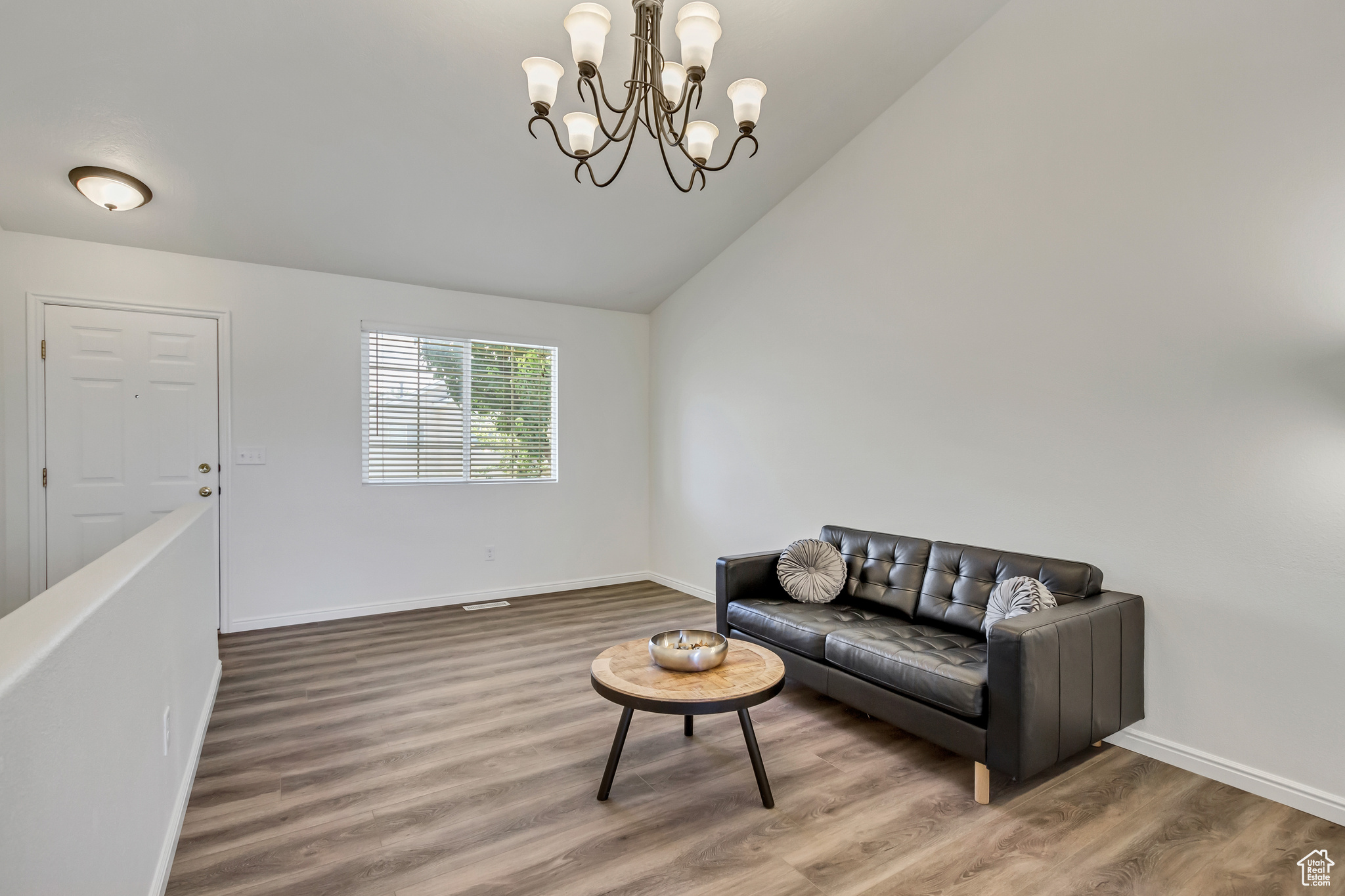 Living room featuring wood-type flooring, high vaulted ceiling, and an inviting chandelier