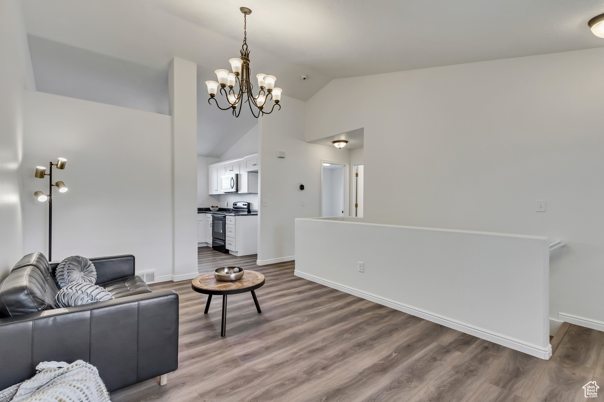 Living room featuring hardwood / wood-style flooring, a notable chandelier, and lofted ceiling