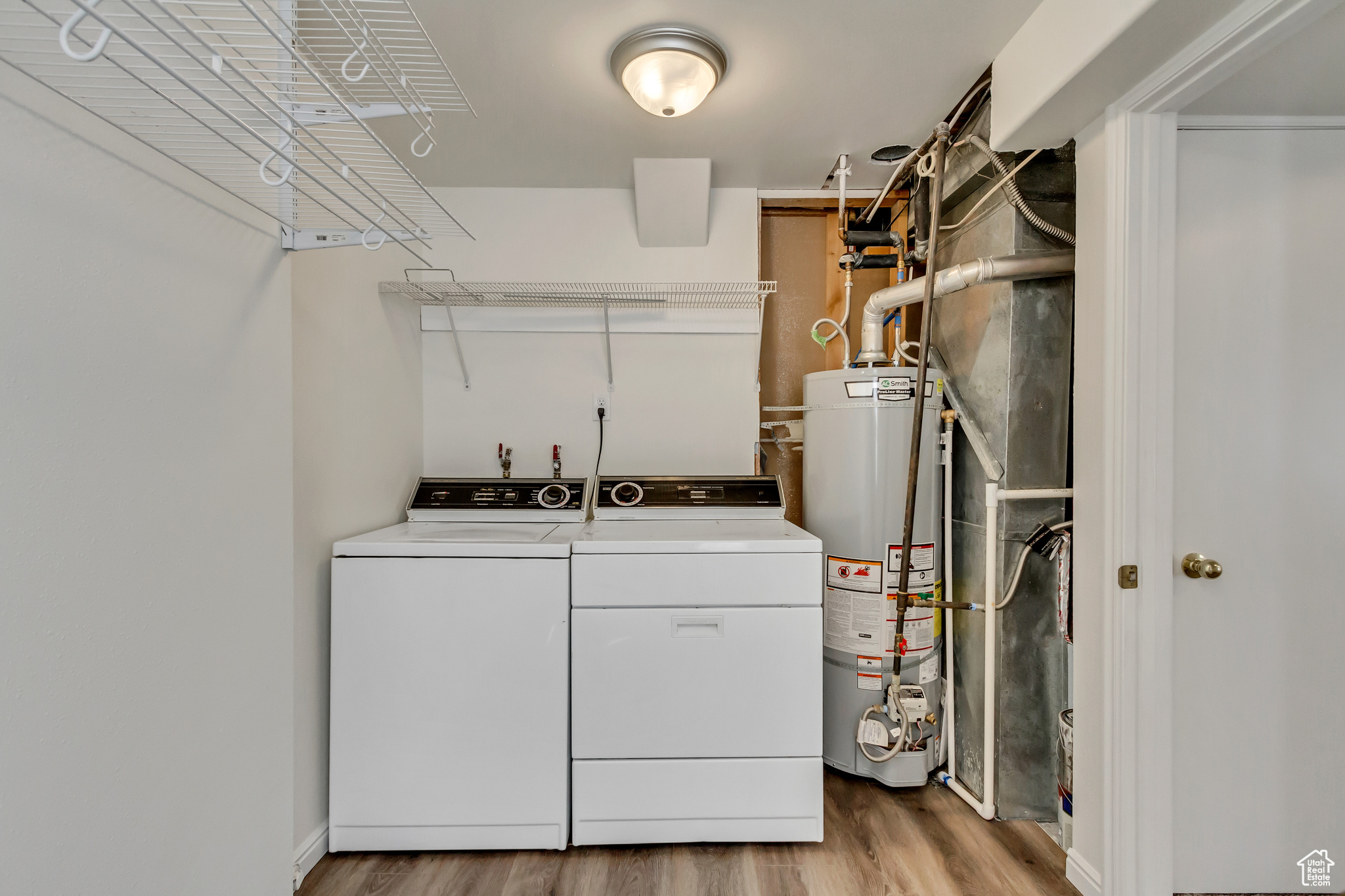 Laundry area featuring washer and clothes dryer, light hardwood / wood-style floors, and gas water heater