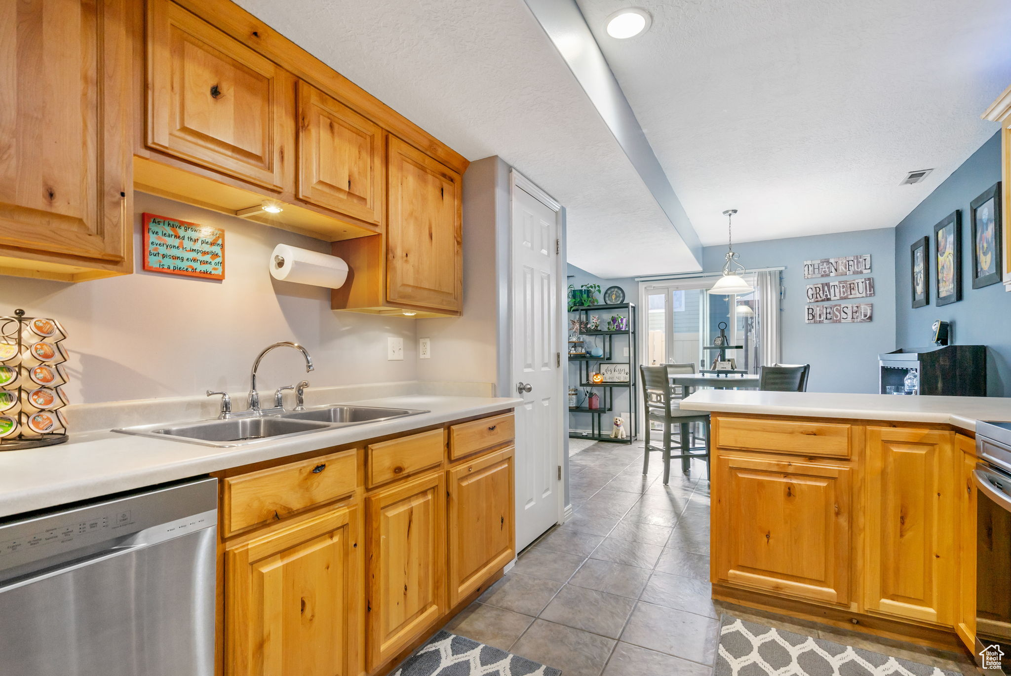 Kitchen featuring hanging light fixtures, tile patterned flooring, stainless steel appliances, and sink