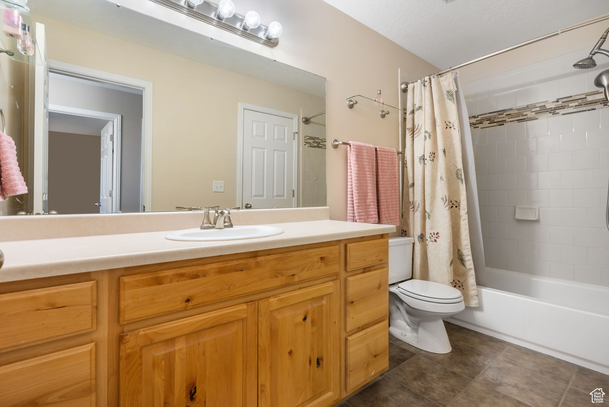 Full bathroom with shower / bath combination with curtain, vanity, and toilet