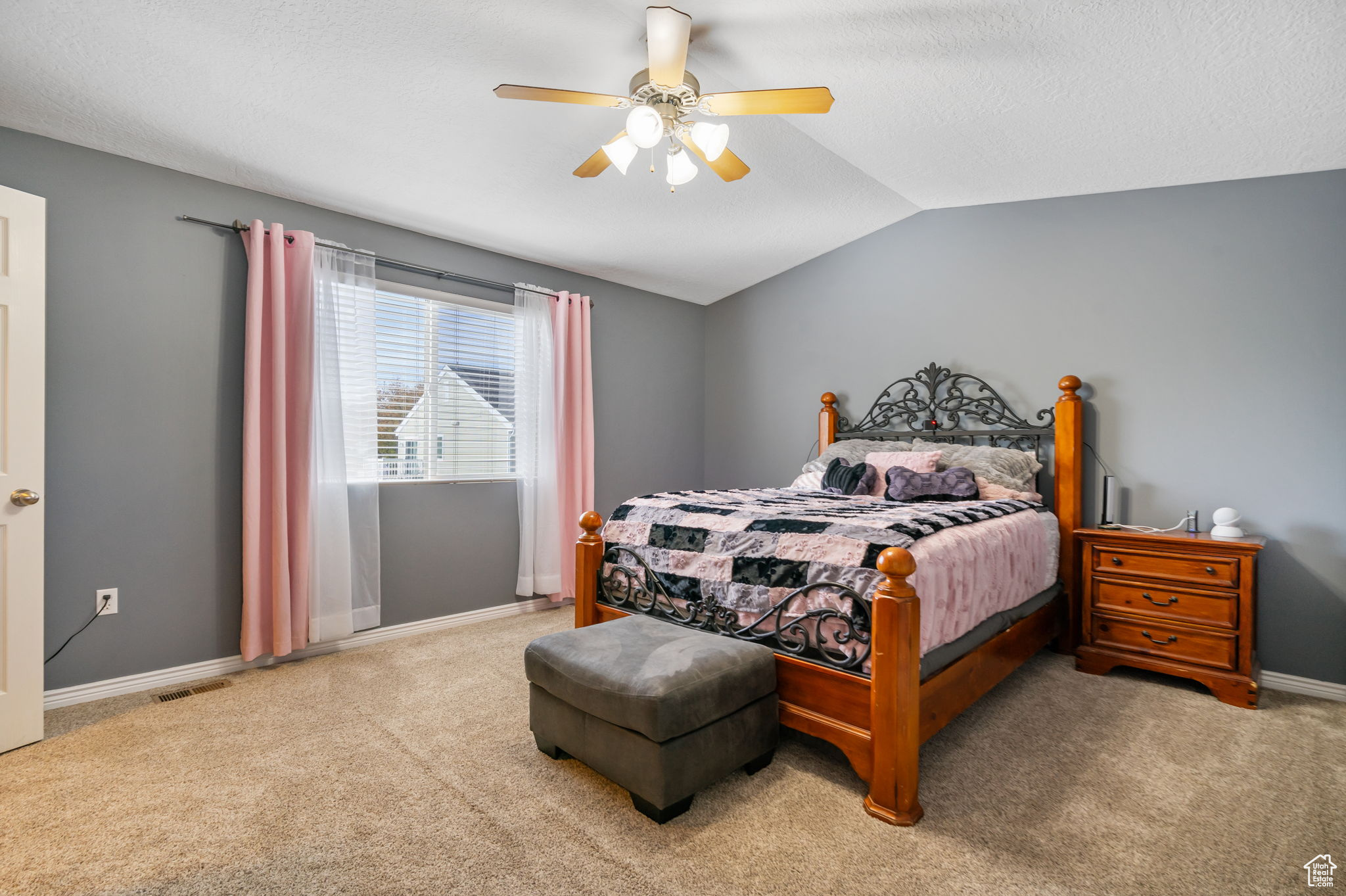 Carpeted bedroom featuring ceiling fan and vaulted ceiling