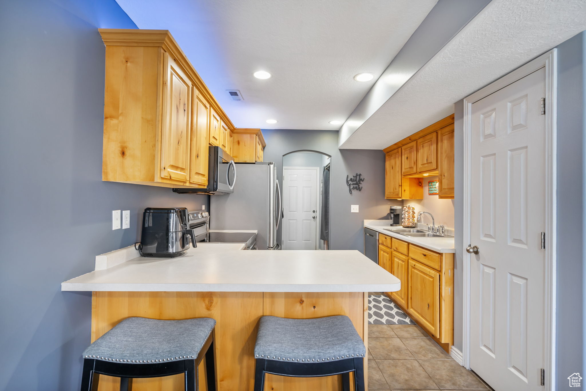 Kitchen featuring sink, stainless steel appliances, kitchen peninsula, a kitchen bar, and light tile patterned flooring