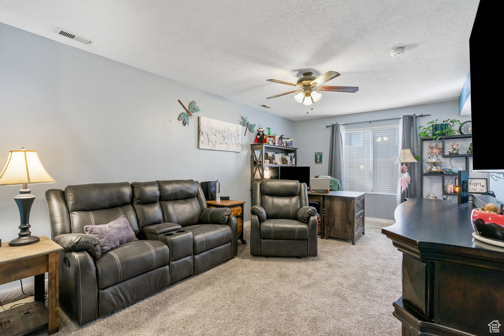 Carpeted living room with a textured ceiling and ceiling fan