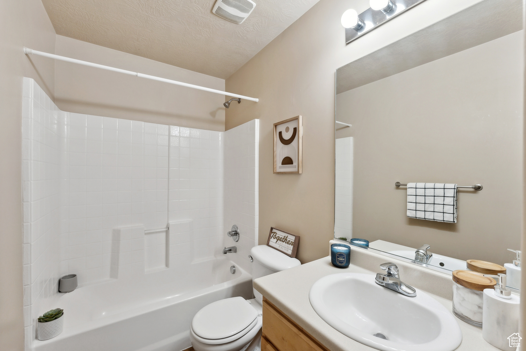 Full bathroom featuring bathtub / shower combination, vanity, a textured ceiling, and toilet