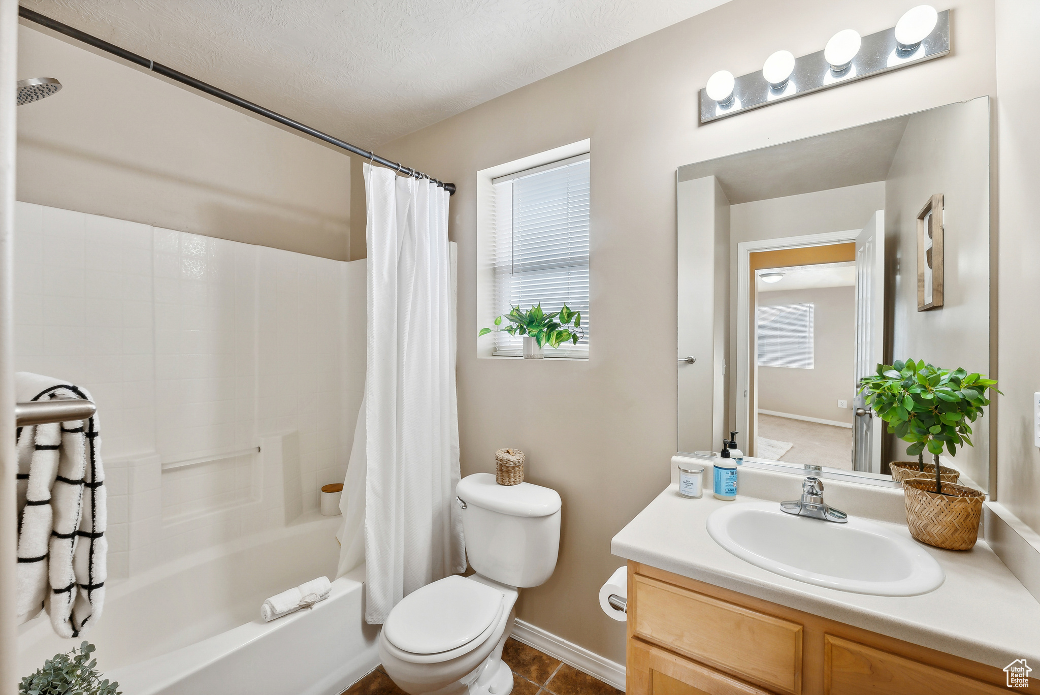 Full bathroom featuring shower / bath combination with curtain, vanity, toilet, and a healthy amount of sunlight