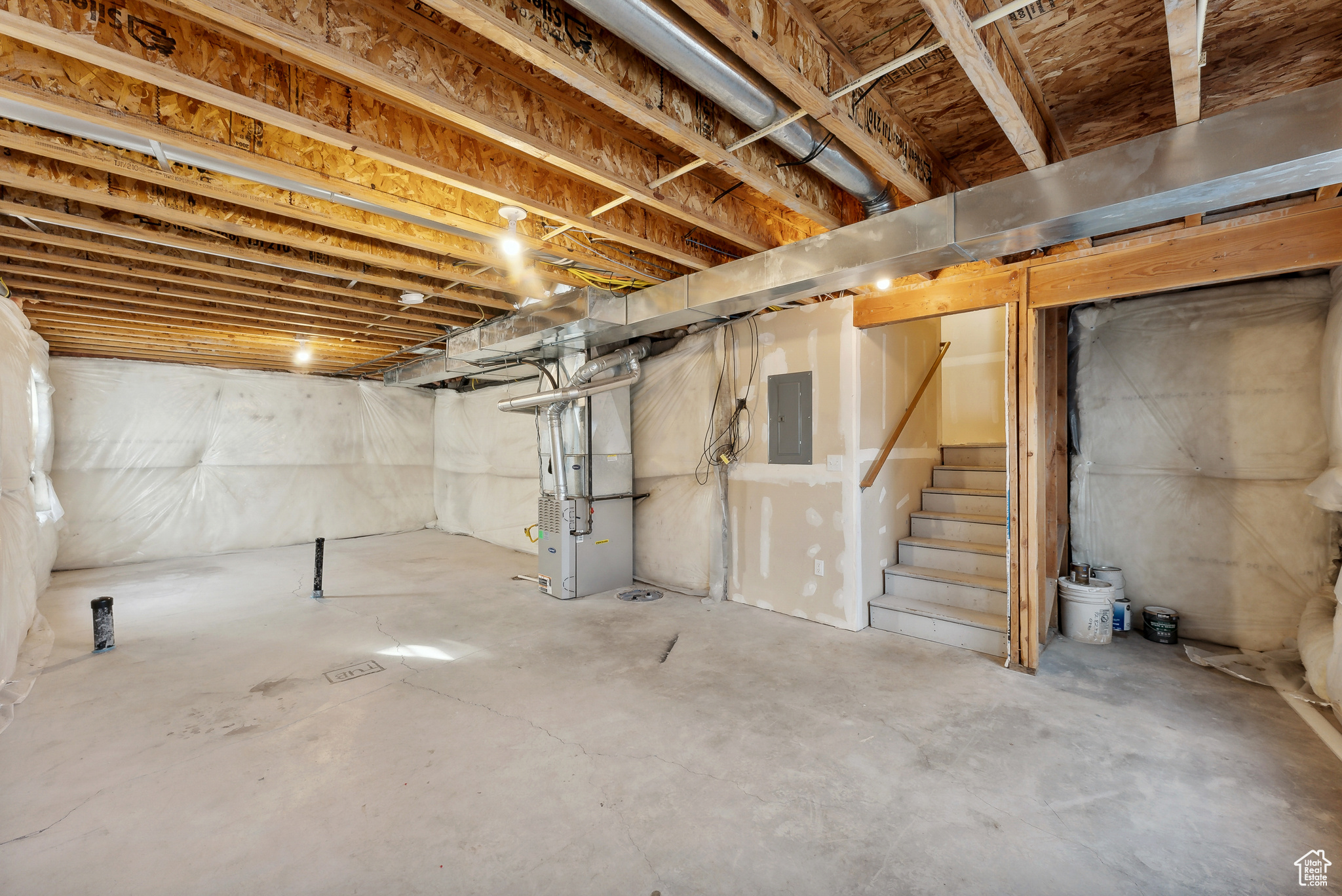 Basement featuring electric panel and heating unit