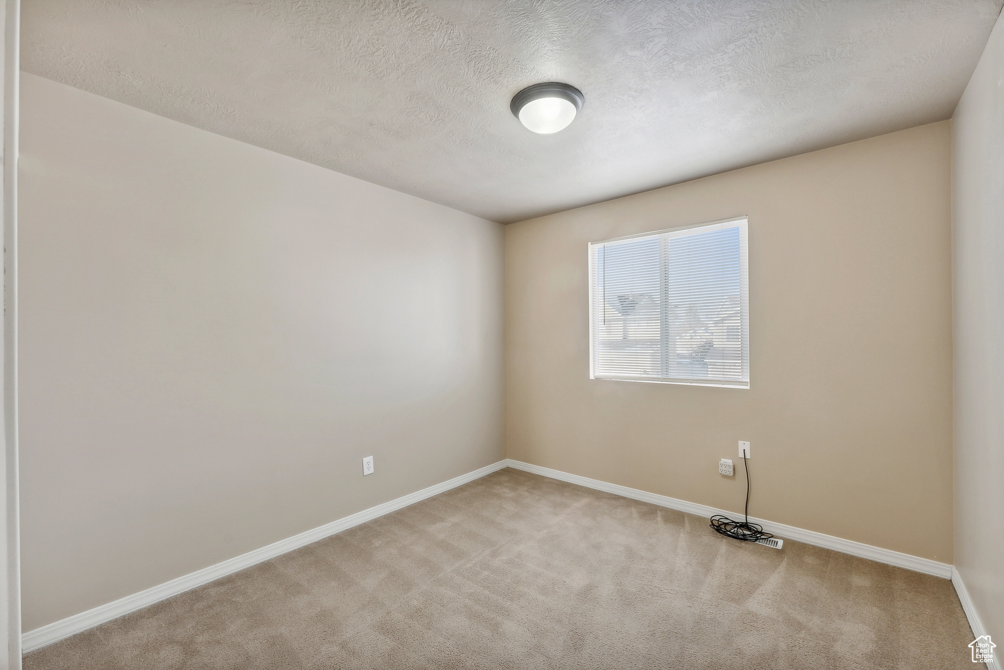 Spare room featuring light colored carpet and a textured ceiling