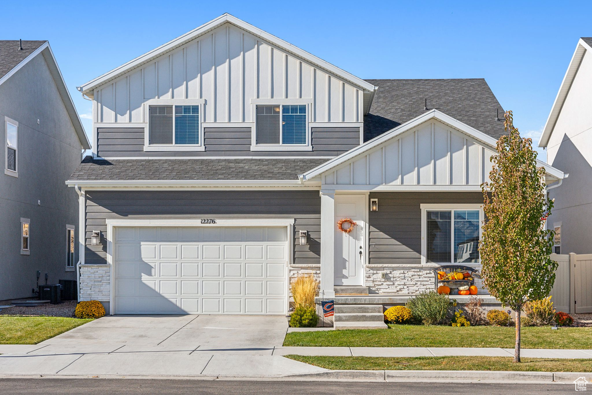 View of front of home with central AC, a front lawn, and a garage