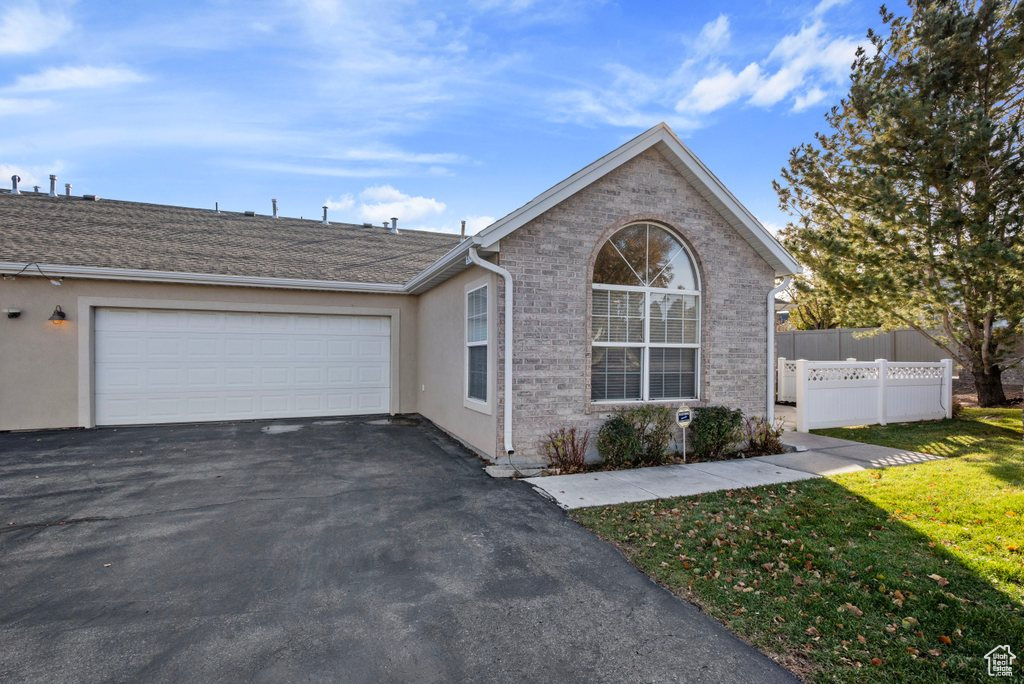 Single story home featuring a garage and a front lawn