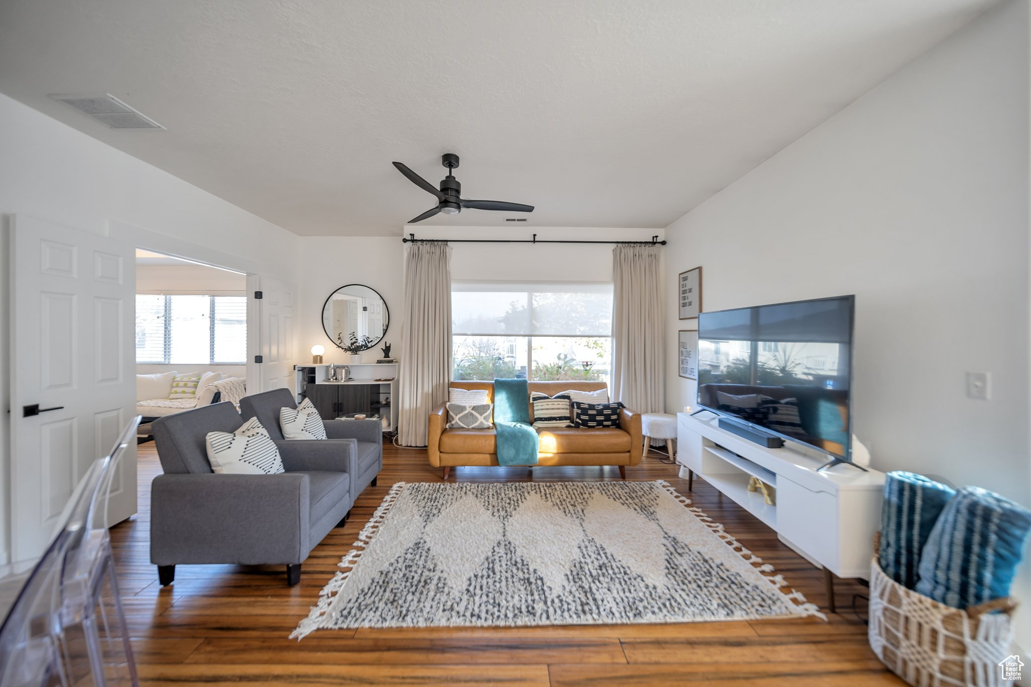 Living room with dark hardwood / wood-style floors, ceiling fan, and a healthy amount of sunlight