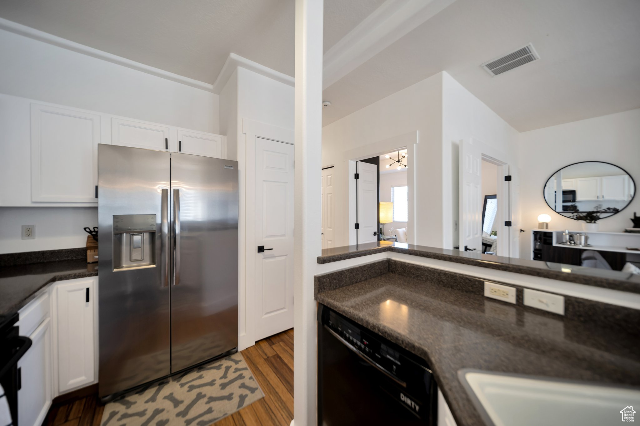 Kitchen with stainless steel refrigerator with ice dispenser, white cabinets, dark hardwood / wood-style flooring, black dishwasher, and crown molding