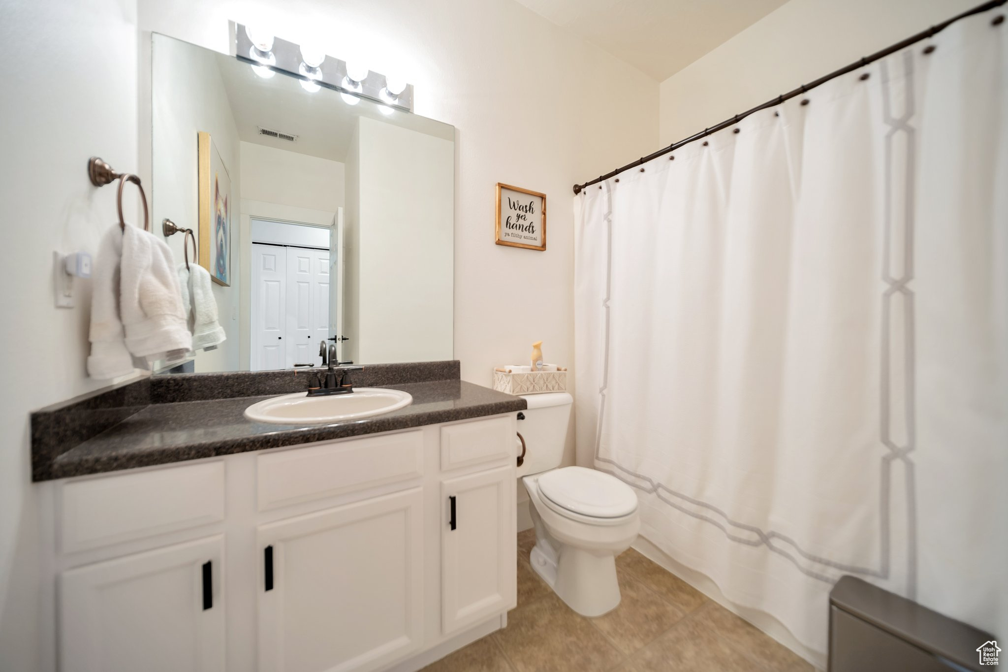 Bathroom featuring tile patterned flooring, vanity, toilet, and curtained shower