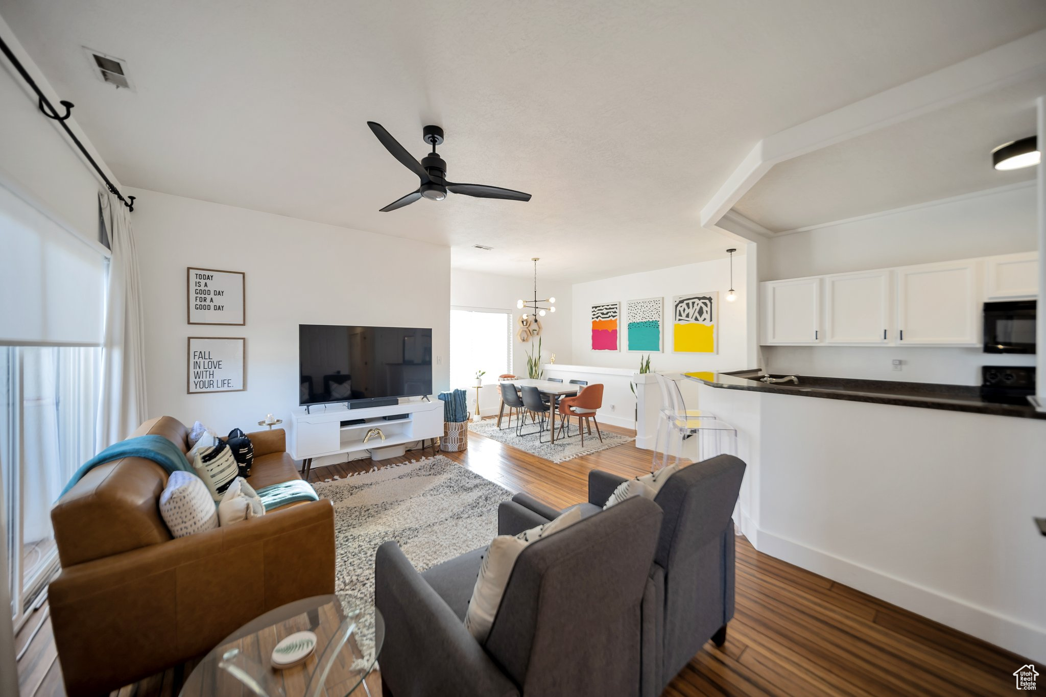 Living room featuring dark wood-type flooring and ceiling fan with notable chandelier