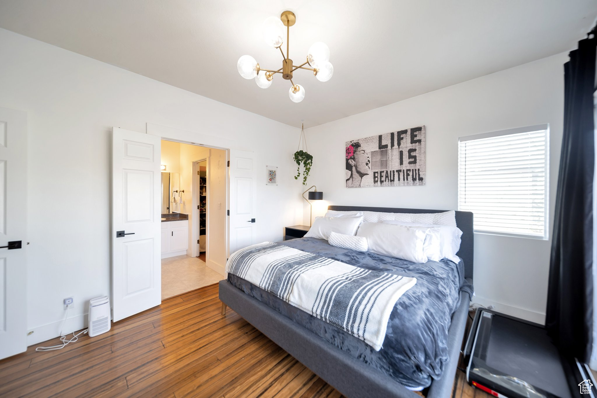 Bedroom with hardwood / wood-style flooring, an inviting chandelier, and ensuite bath