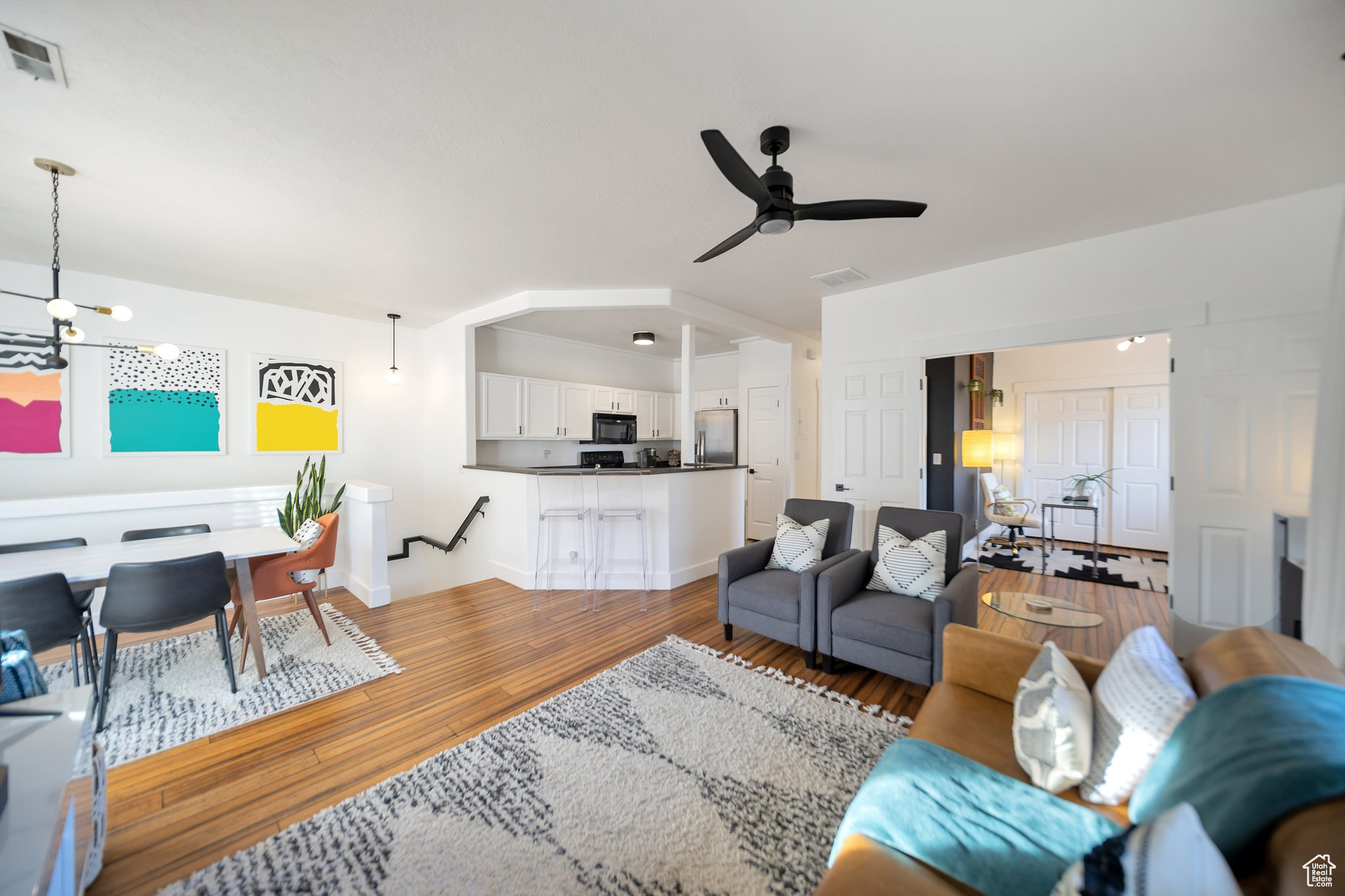 Living room featuring ceiling fan with notable chandelier and hardwood / wood-style flooring