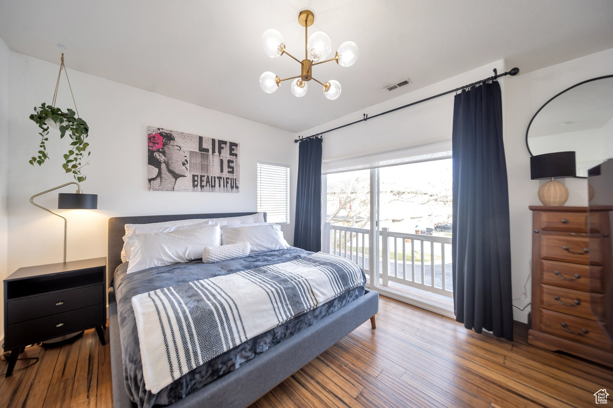 Bedroom featuring wood-type flooring, access to outside, and an inviting chandelier