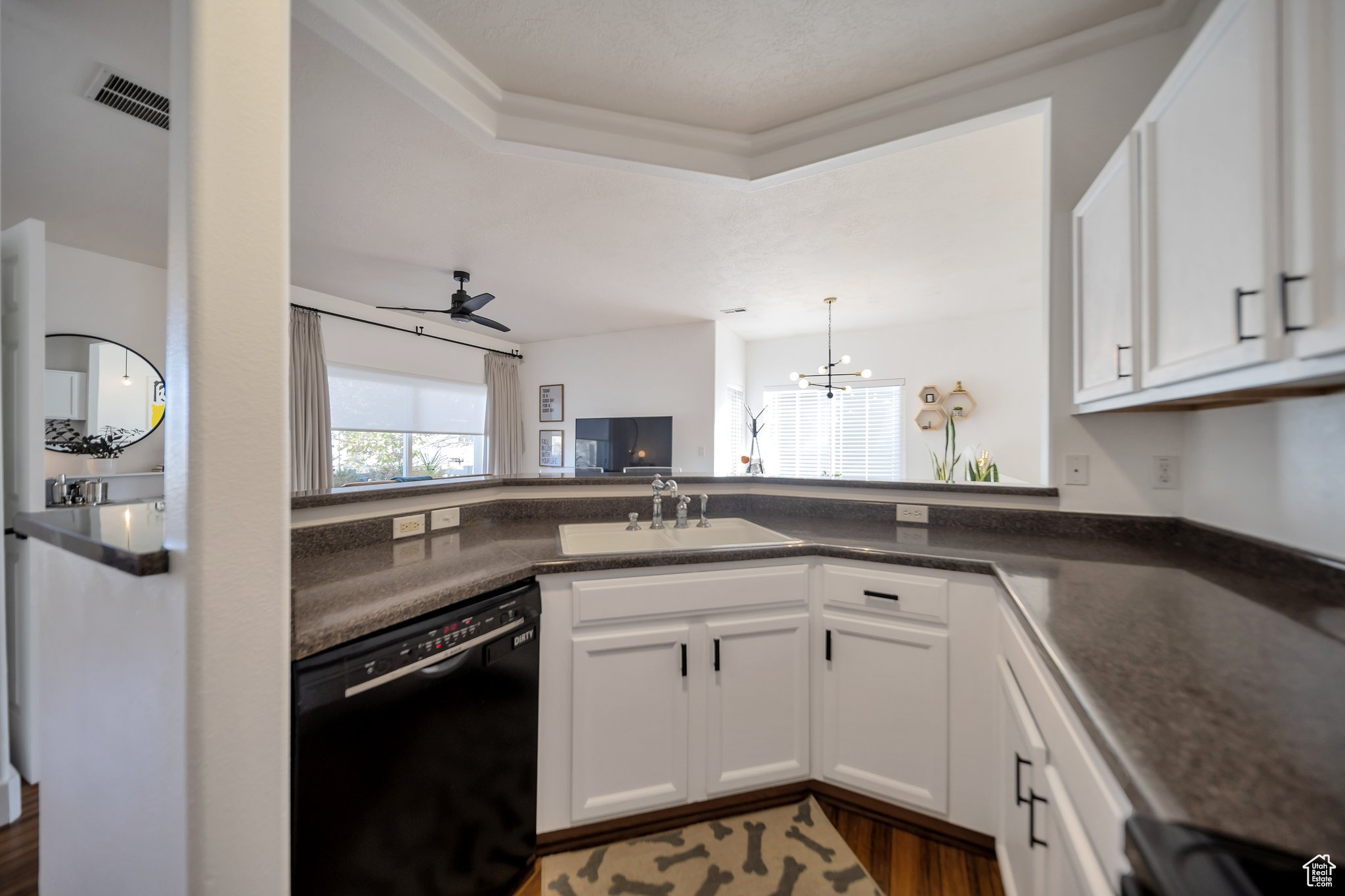 Kitchen with white cabinetry, sink, black dishwasher, and dark hardwood / wood-style floors