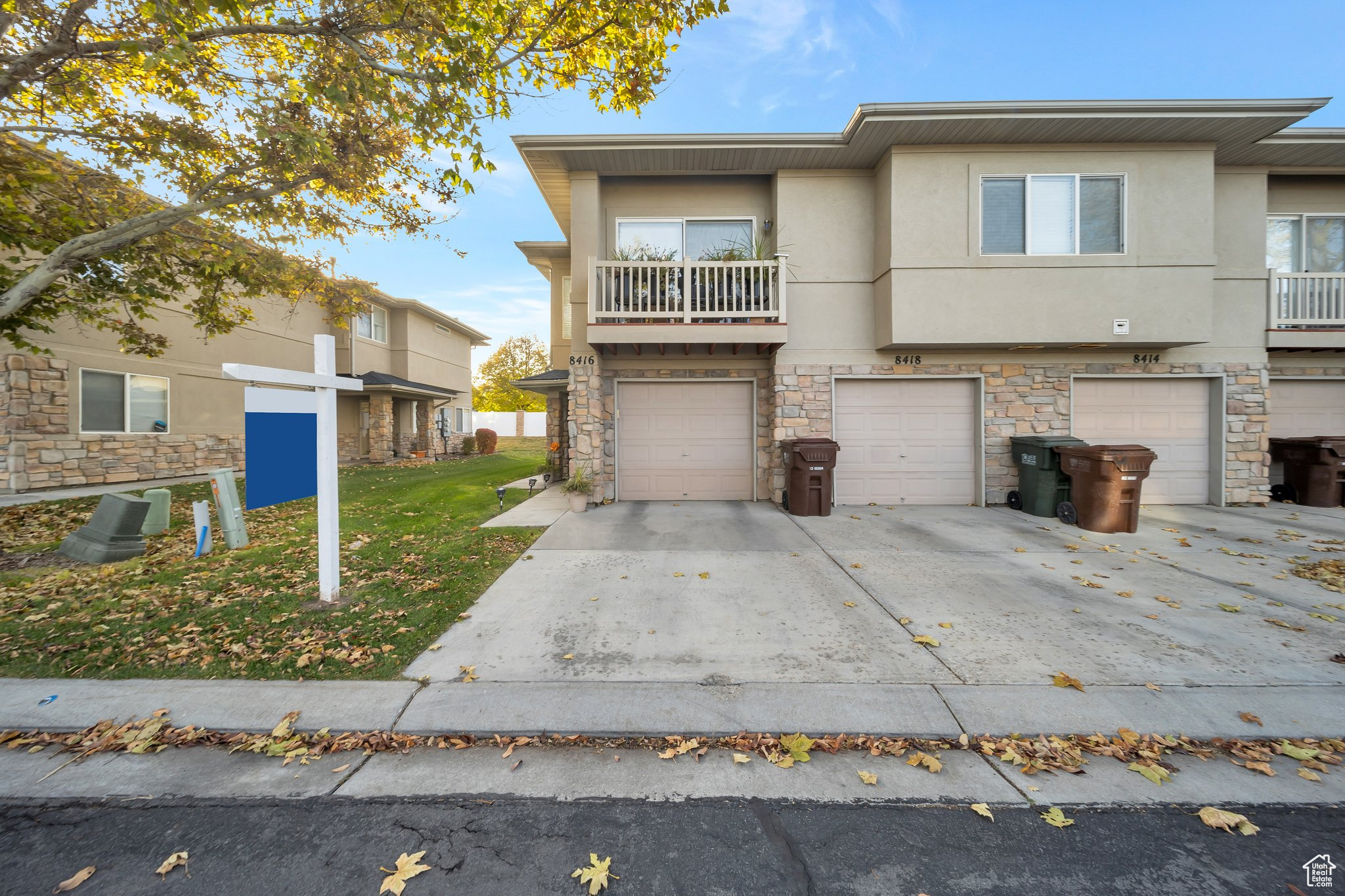 View of property featuring a balcony, a front yard, and a garage