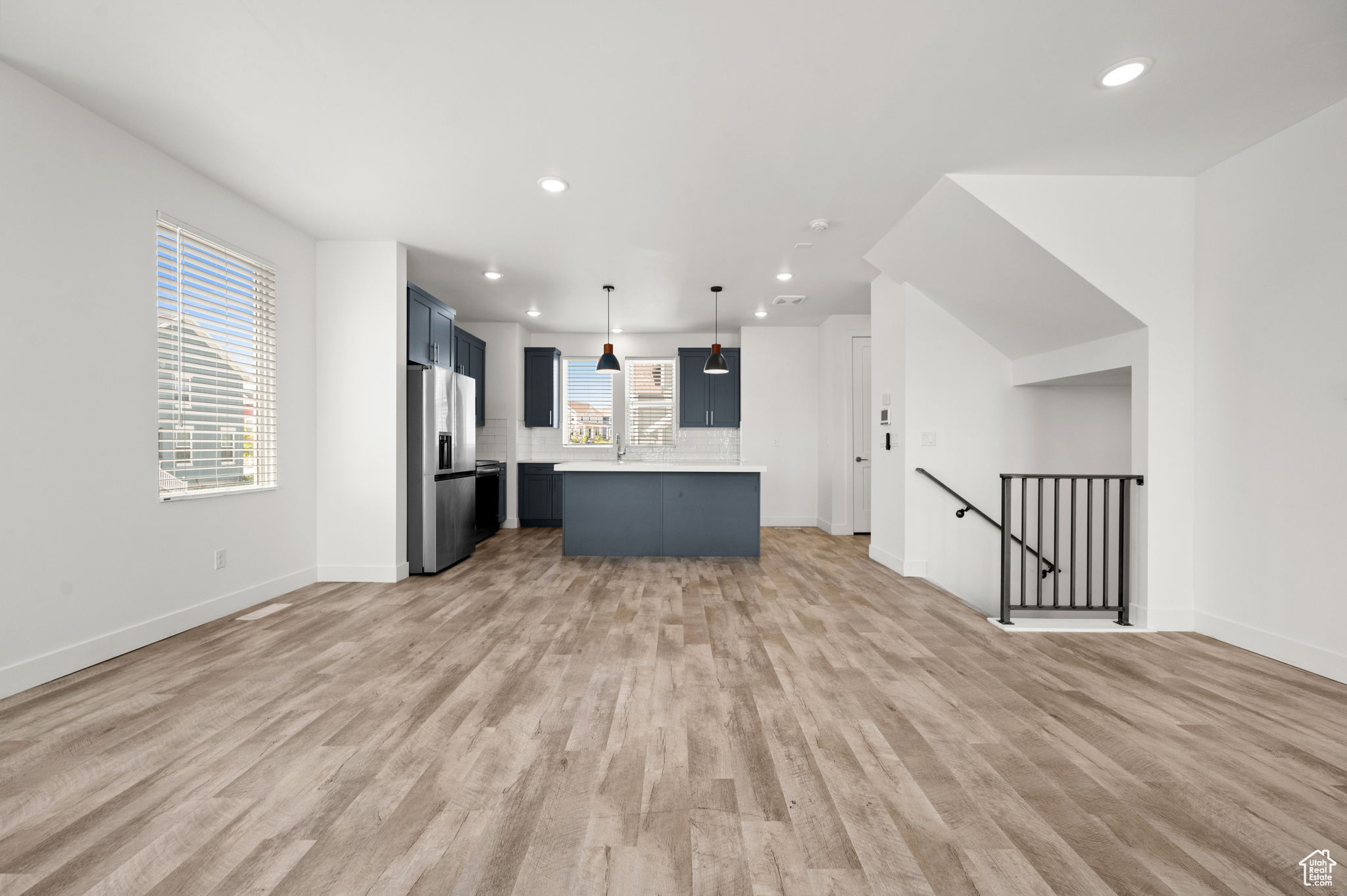 Kitchen with light hardwood / wood-style floors, a center island, stainless steel fridge, and a healthy amount of sunlight