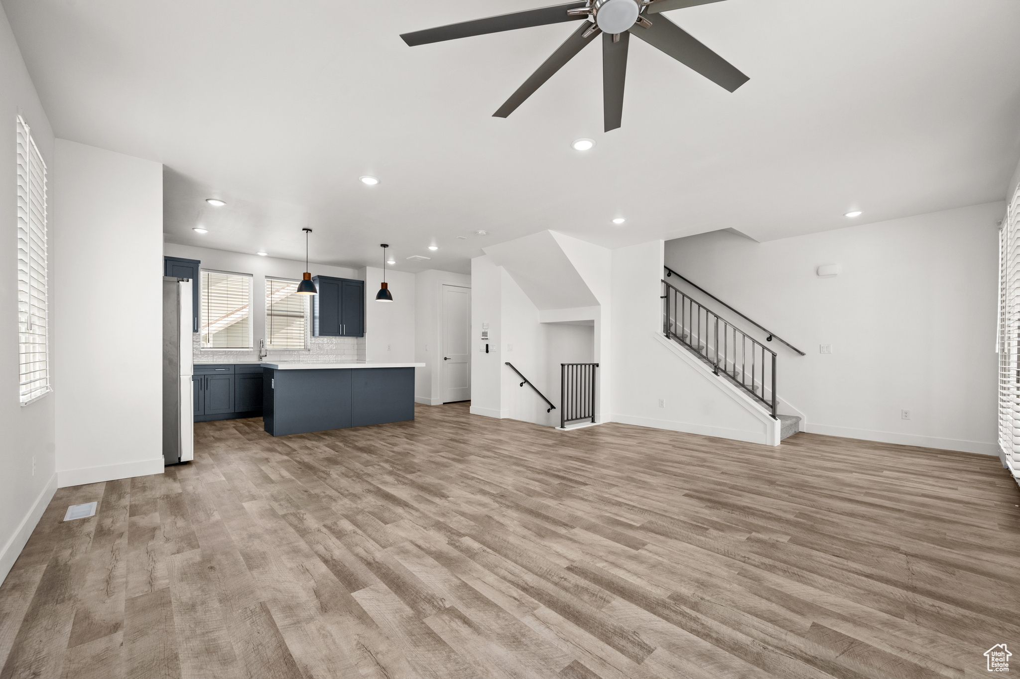 Unfurnished living room with light wood-type flooring and ceiling fan