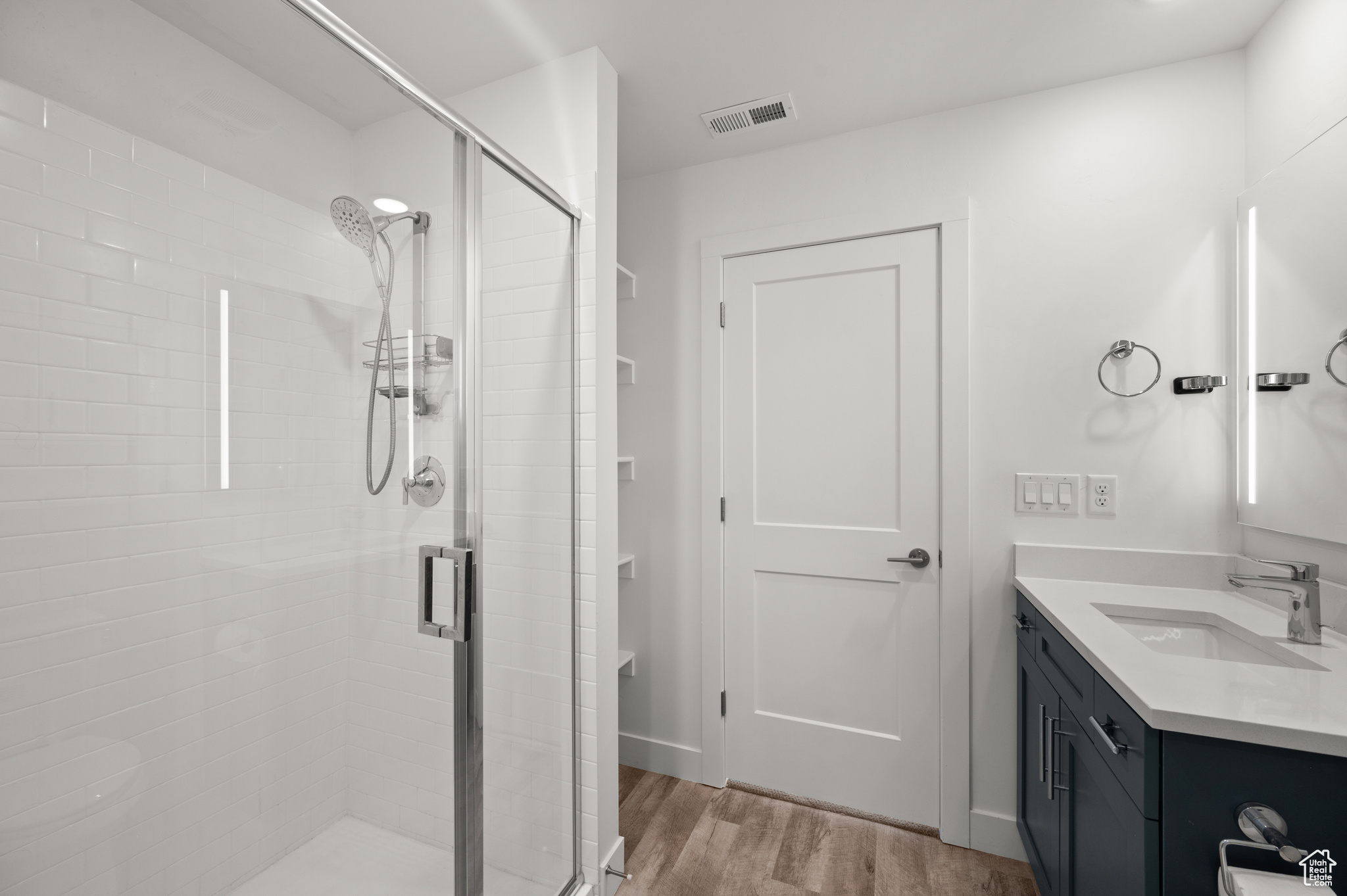 Bathroom featuring wood-type flooring, vanity, and walk in shower