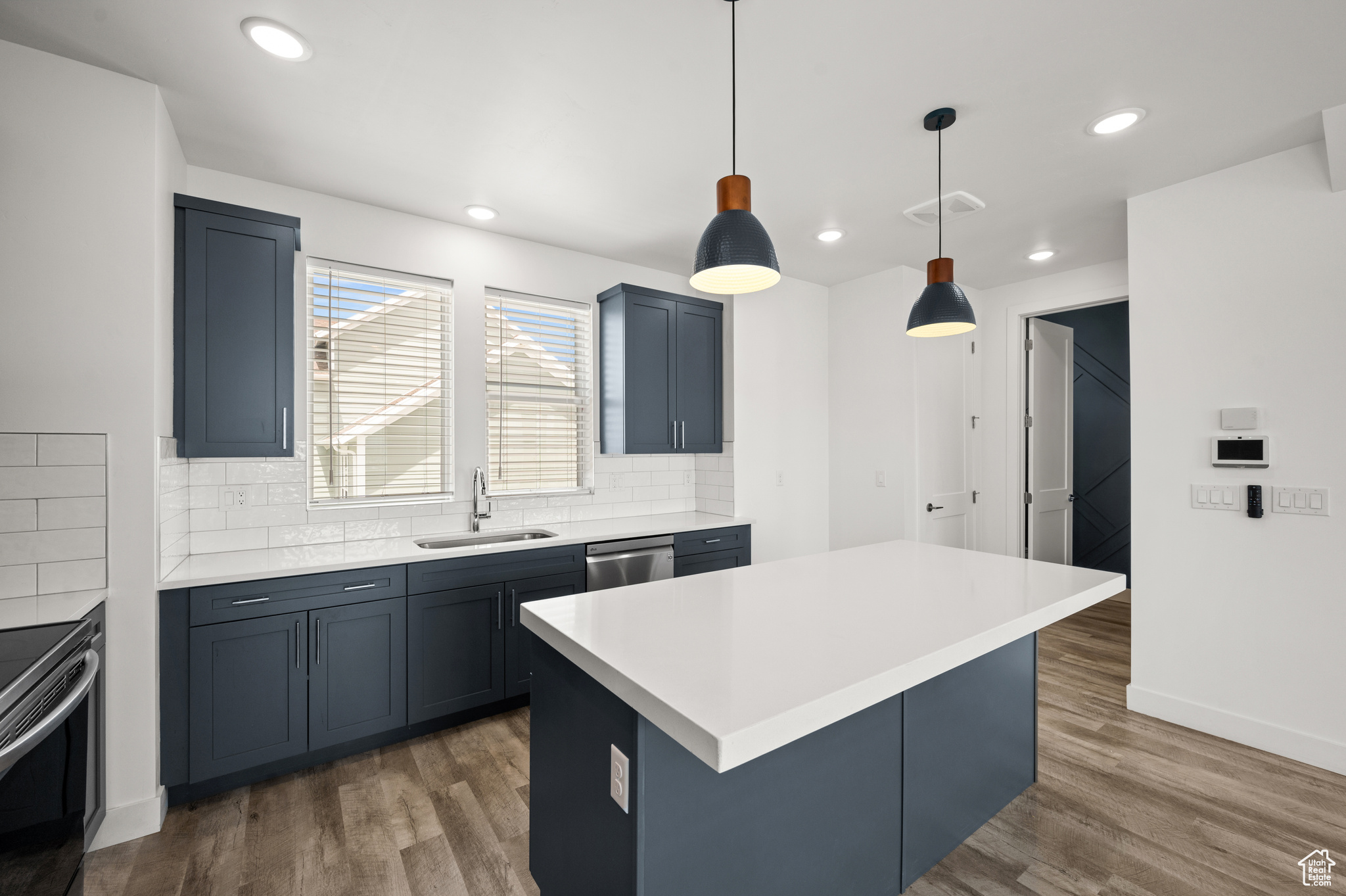 Kitchen with a center island, dark wood-type flooring, sink, tasteful backsplash, and decorative light fixtures