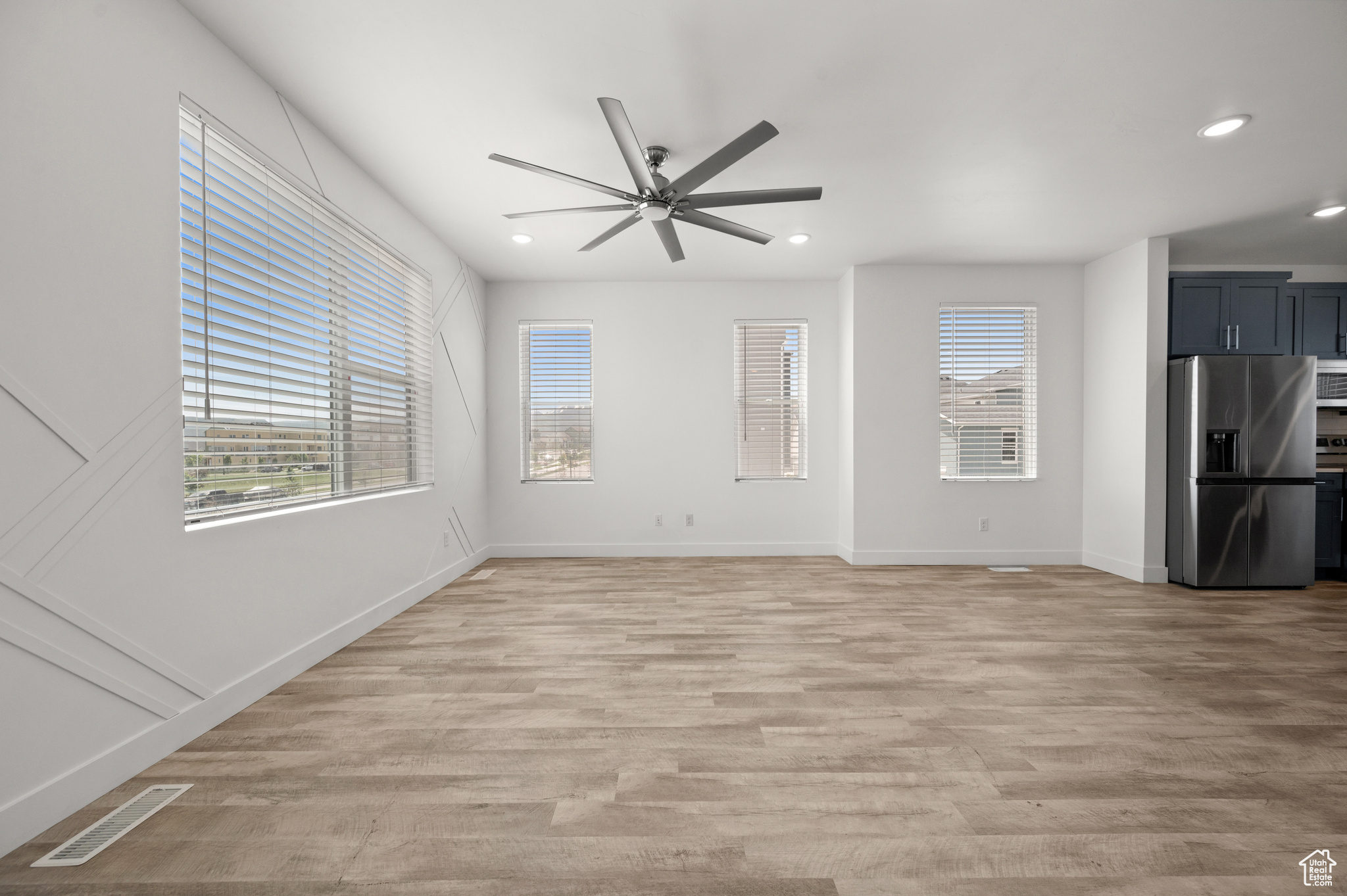 Unfurnished living room featuring ceiling fan and light wood-type flooring