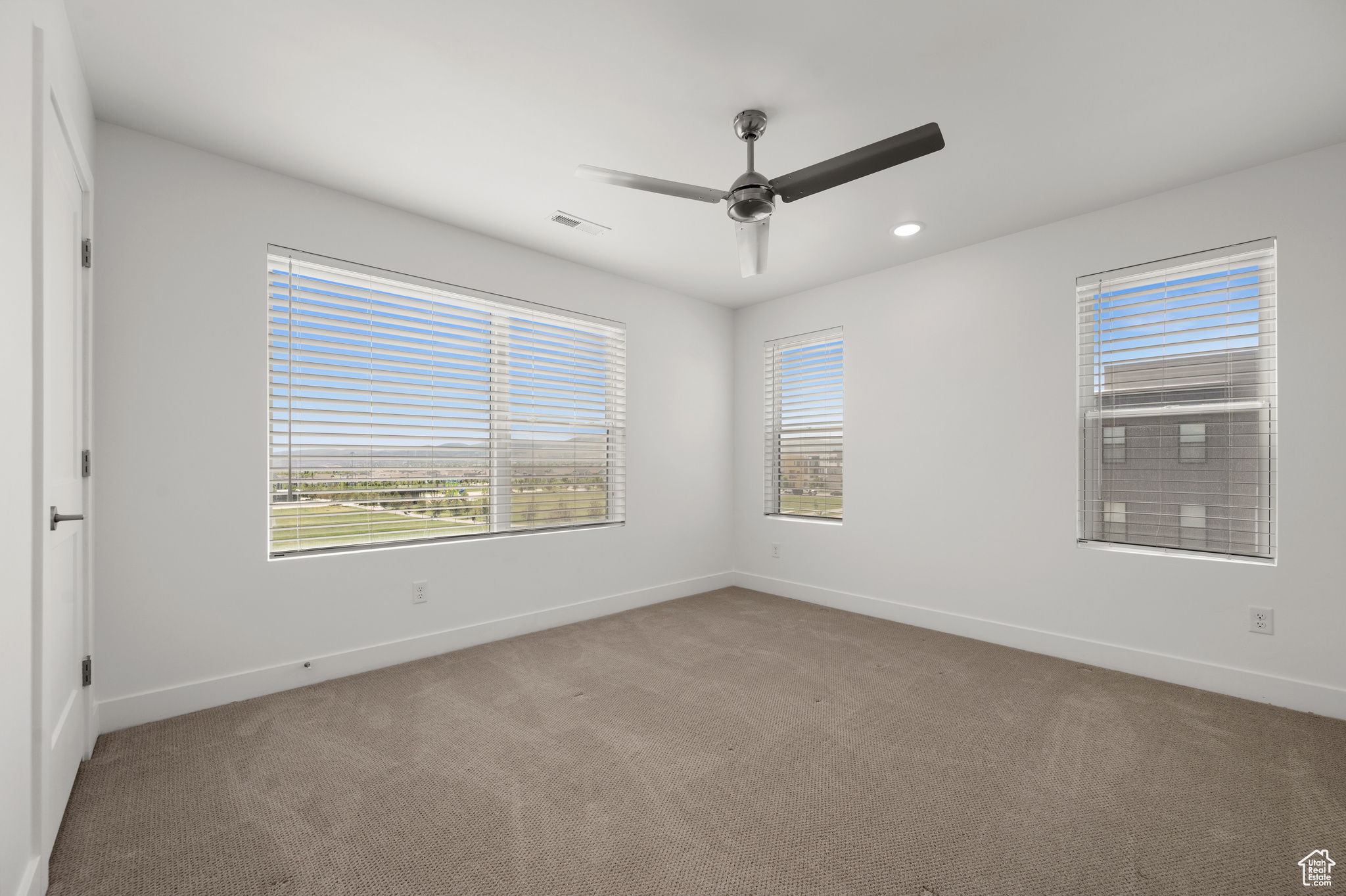 Carpeted empty room with ceiling fan and a healthy amount of sunlight