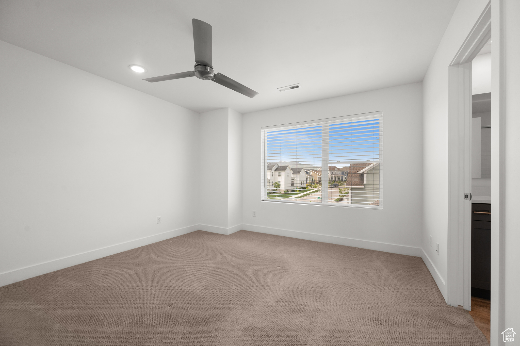 Carpeted spare room featuring ceiling fan