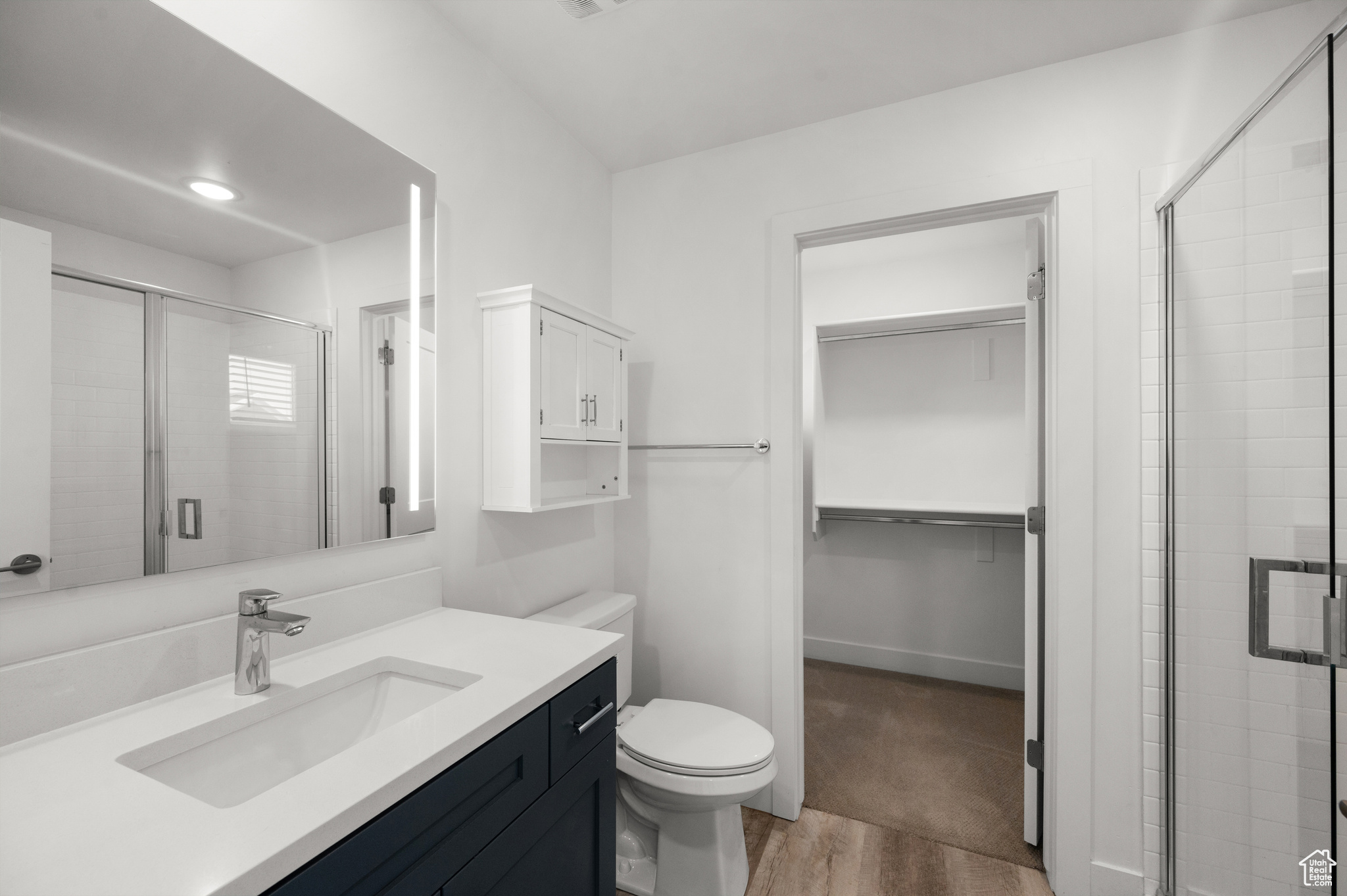 Bathroom featuring hardwood / wood-style floors, vanity, an enclosed shower, and toilet