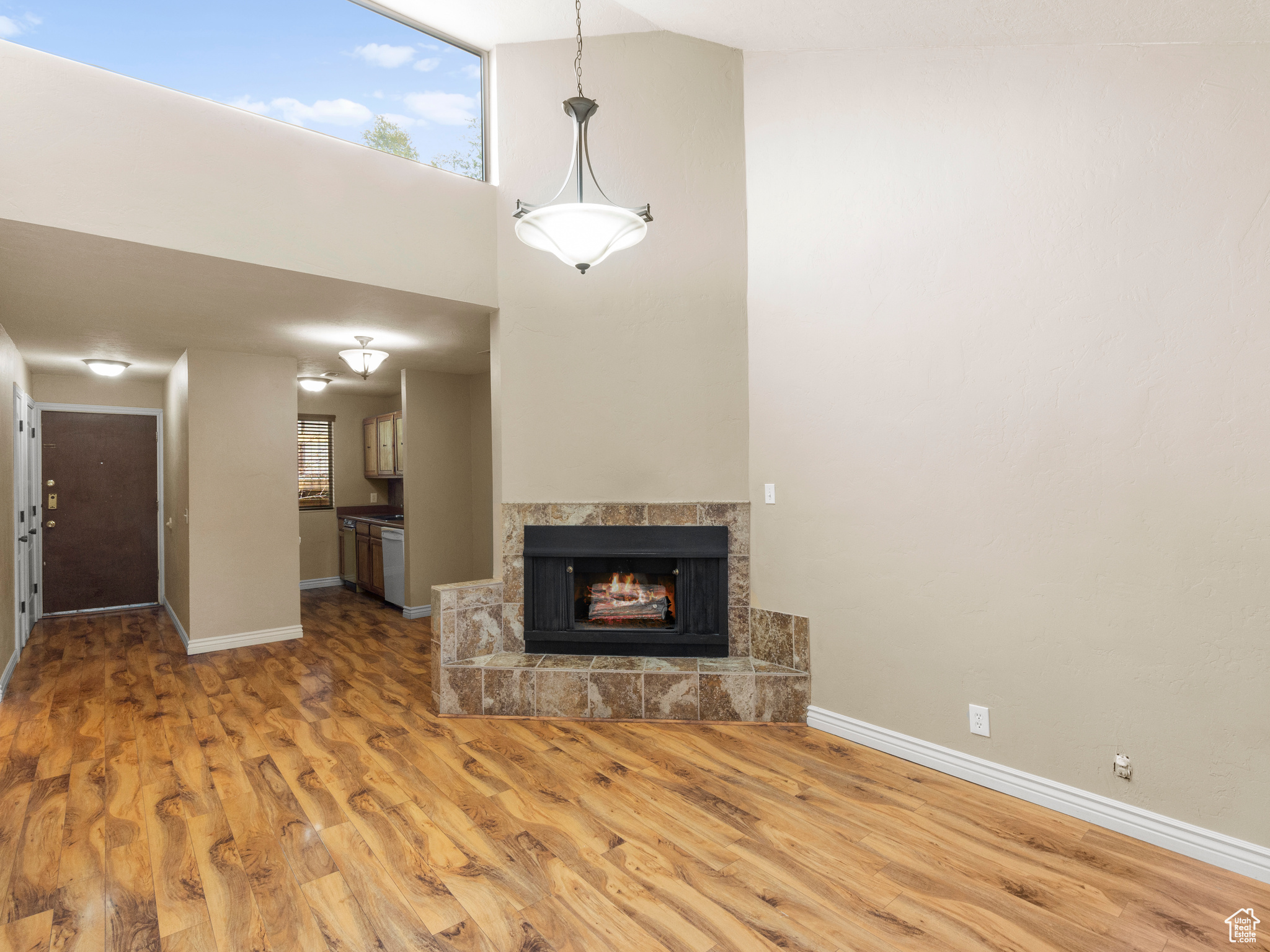 Unfurnished living room featuring wood-type flooring, a fireplace, and high vaulted ceiling