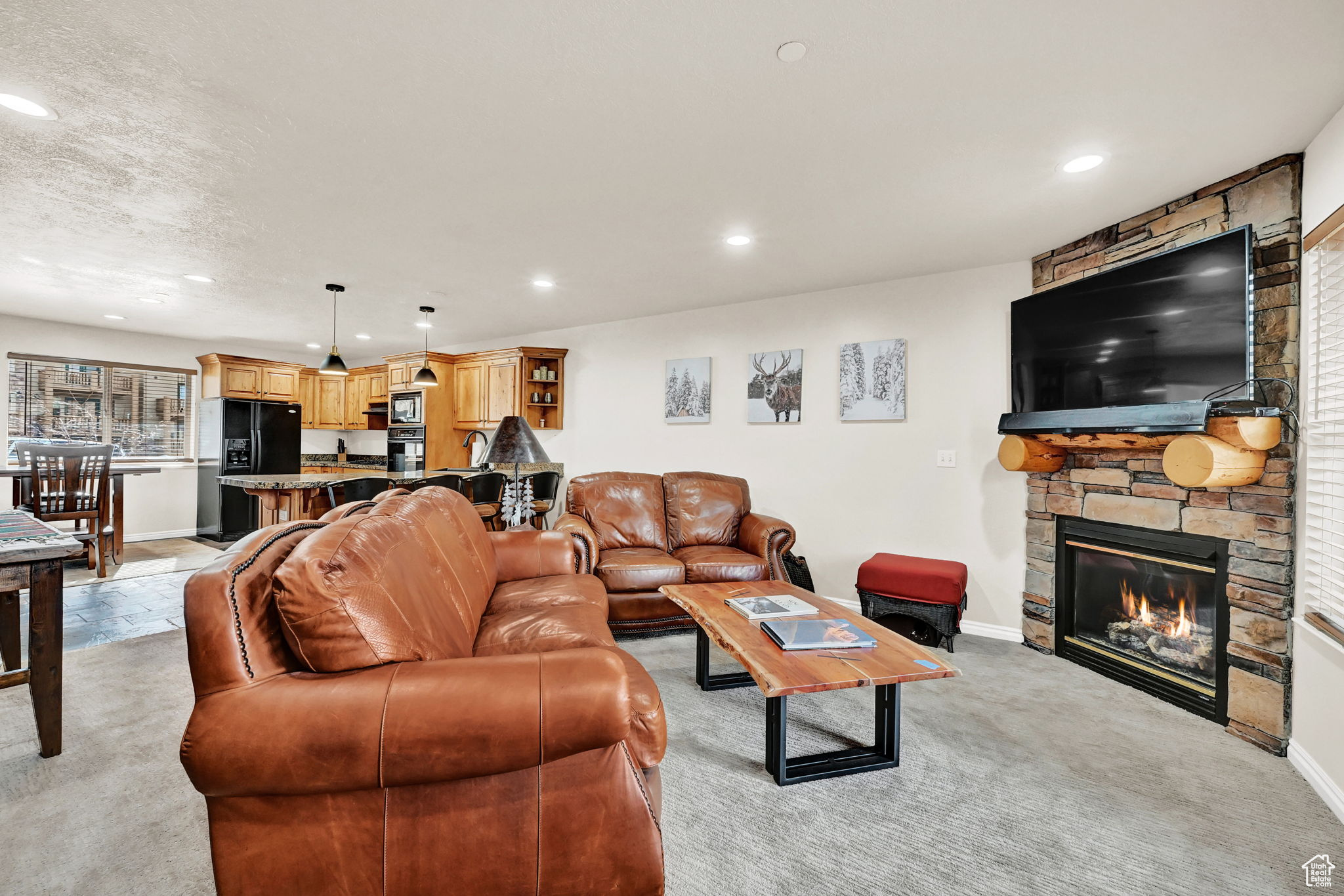 Carpeted living room featuring a stone fireplace