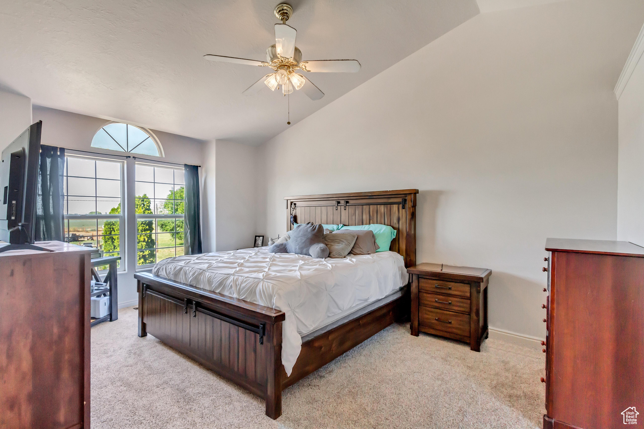 Carpeted bedroom featuring ceiling fan and vaulted ceiling