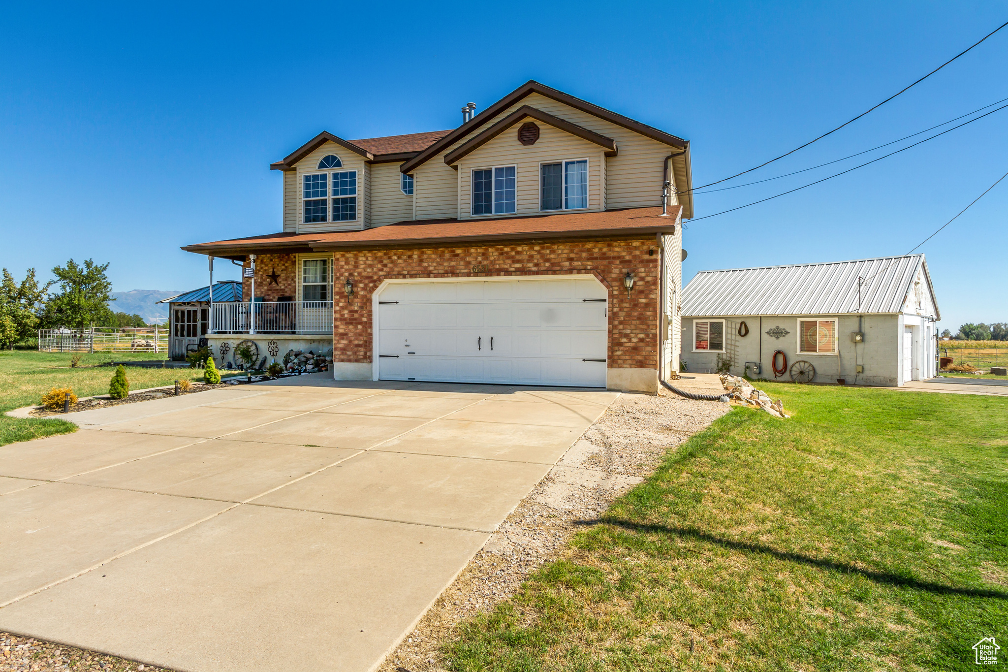 View of front of property with covered porch, a garage, and a front lawn