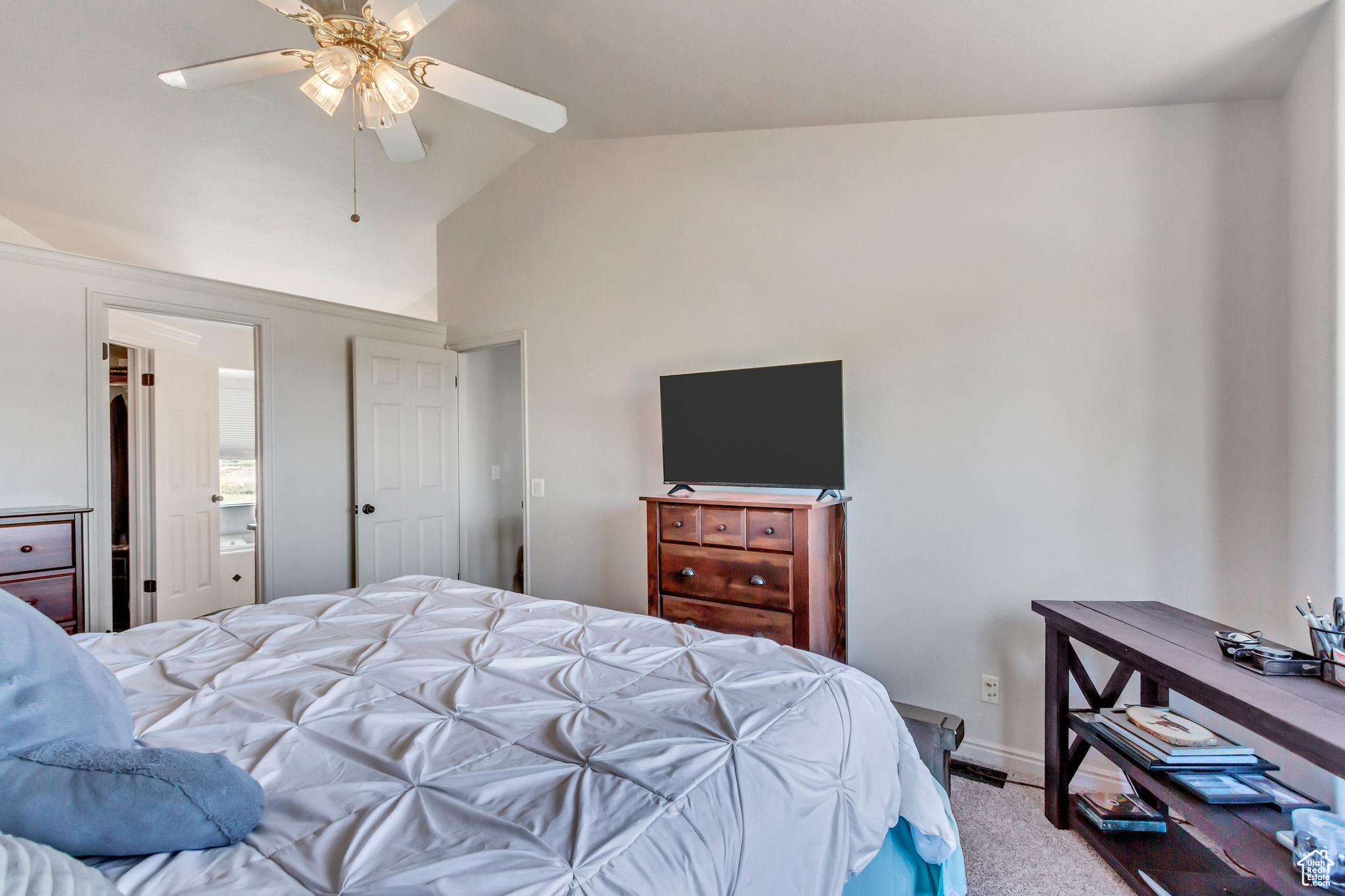 Bedroom with carpet flooring, connected bathroom, vaulted ceiling, and ceiling fan