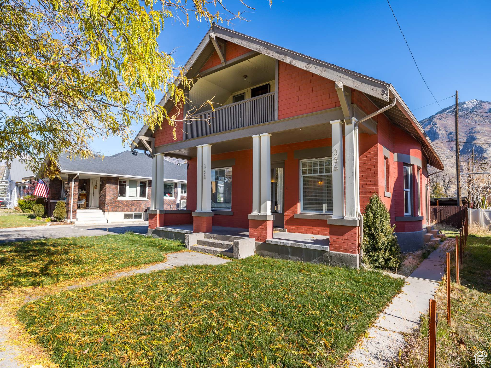 View of front facade with a mountain view, covered porch, a balcony, and a front lawn