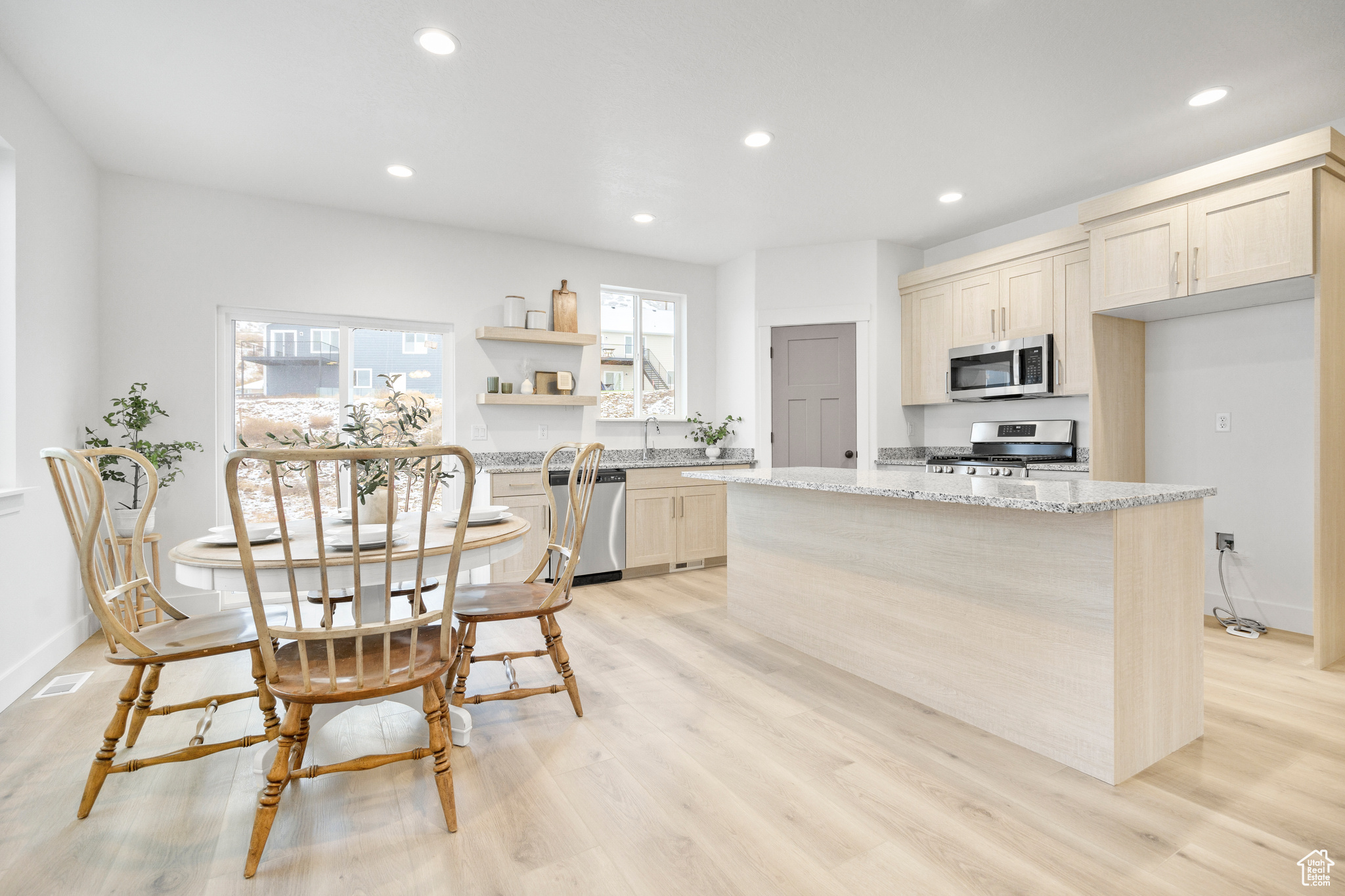 Kitchen featuring light stone counters, a center island, a healthy amount of sunlight, and appliances with stainless steel finishes