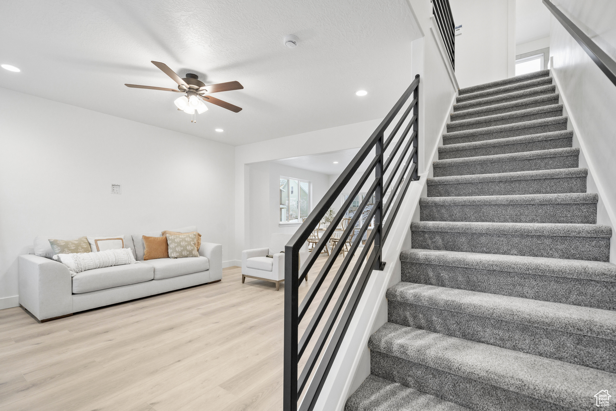 Stairs with hardwood / wood-style flooring and ceiling fan